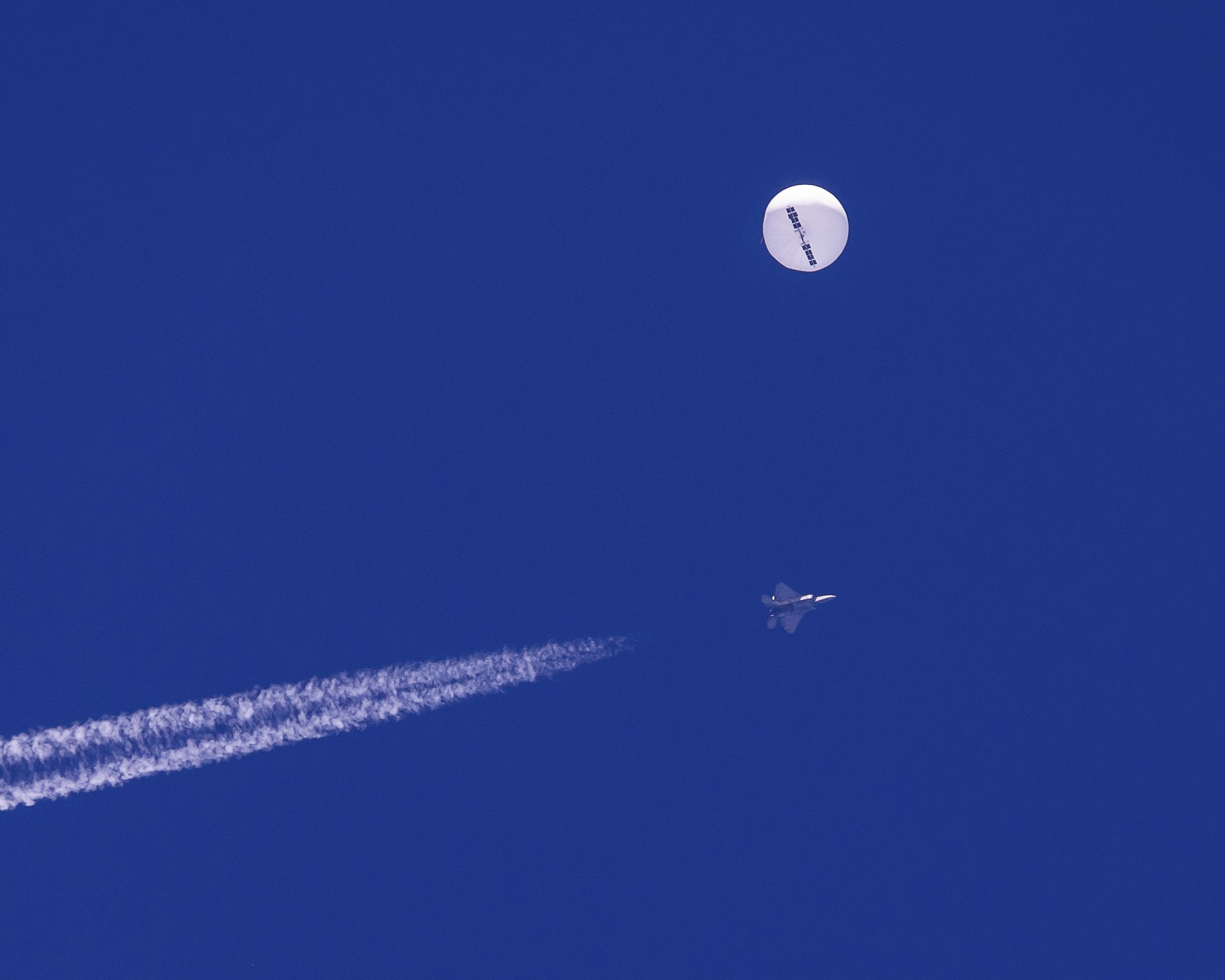 A large balloon drifts above the Atlantic Ocean, just off the coast of South Carolina, with a fighter jet and its contrail seen below it on Feb. 4. The balloon was struck by a missile from an F-22 fighter just off Myrtle Beach.
