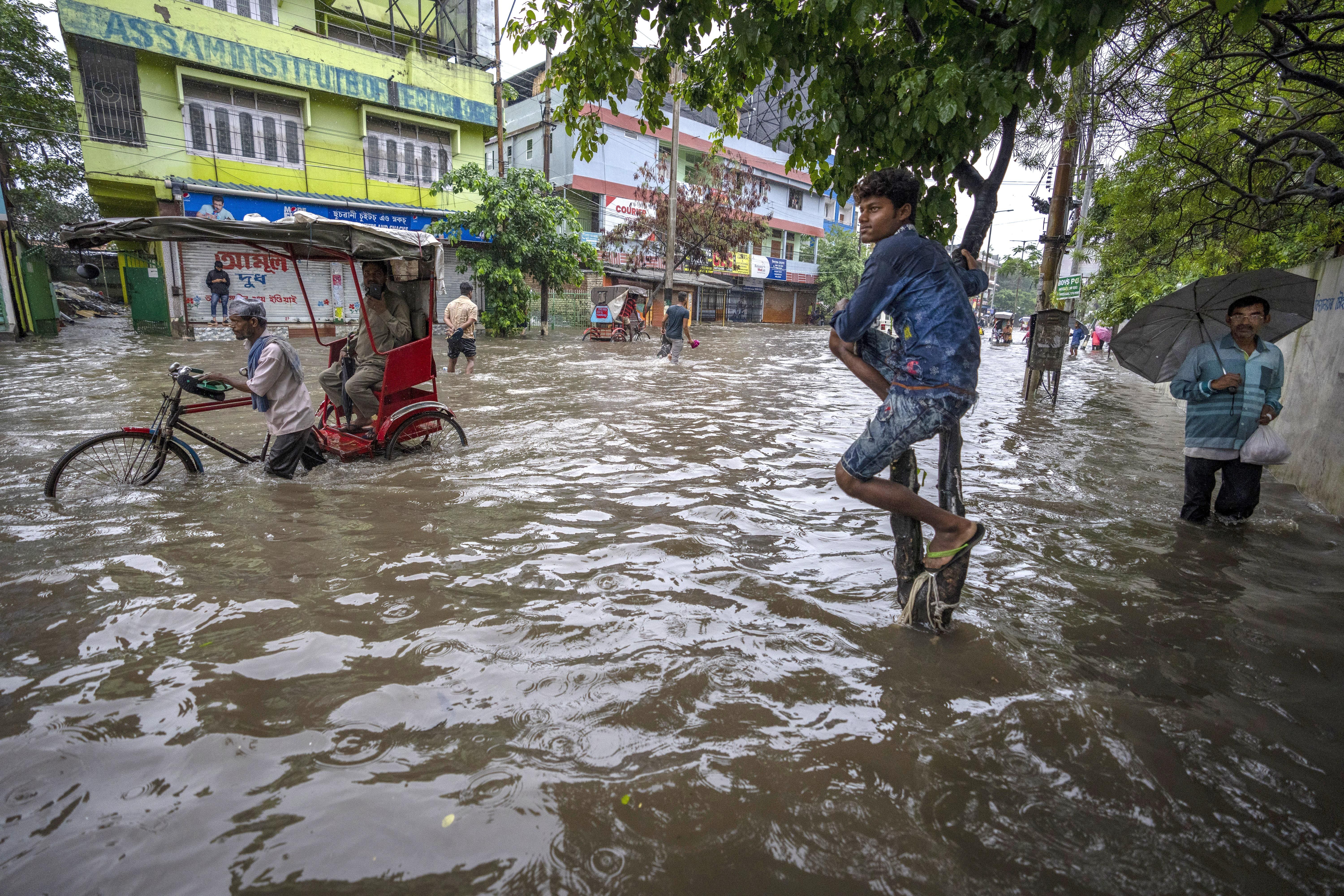 People wade through a flooded road after heavy rains in Gauhati, Assam state, India, on June 14, 2022. Due to most glaciers being "out of balance" with the current climate, new research says 15 million people could lose their lives in glacial lake outburst floods.