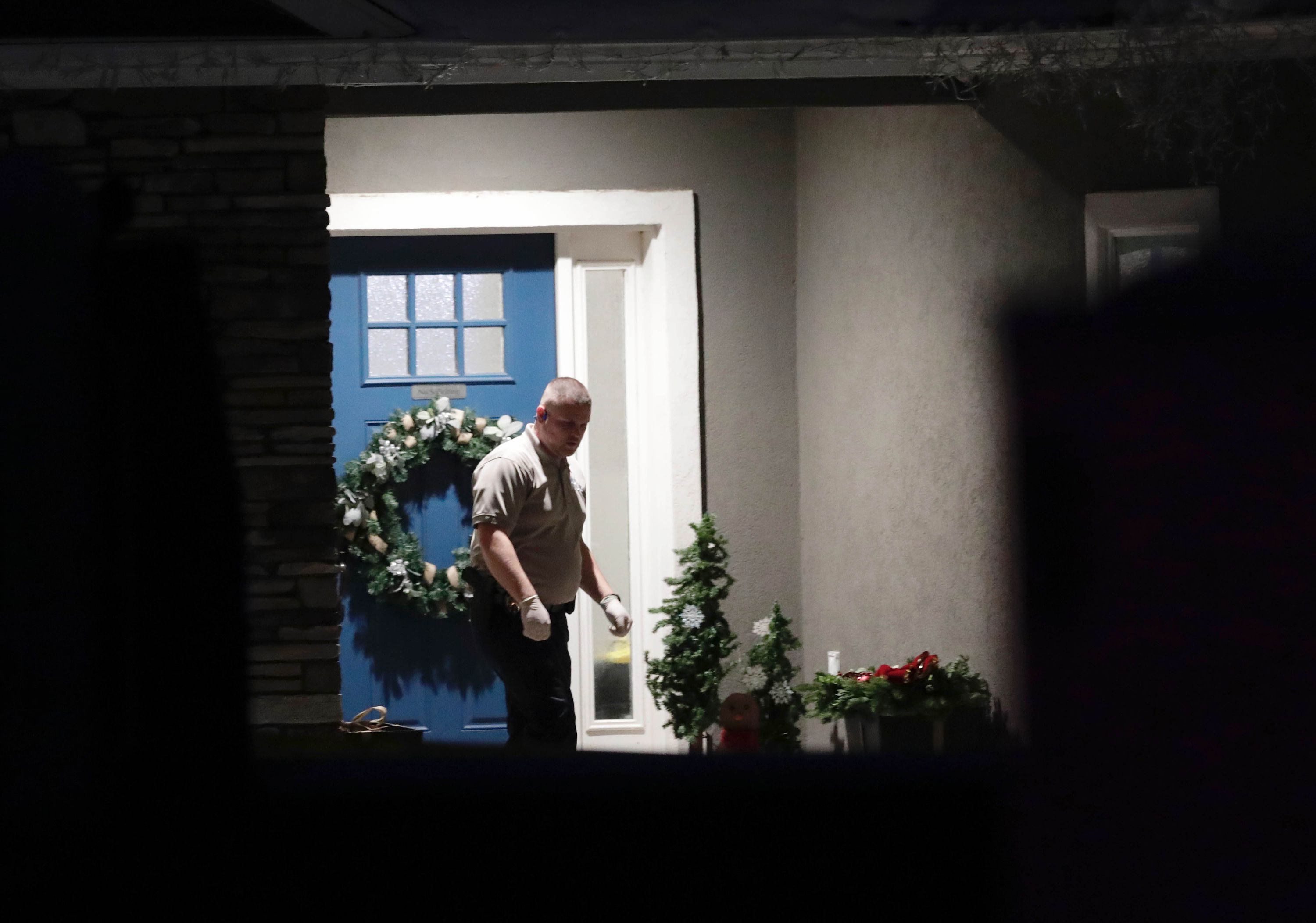 A law enforcement official stands at the front door of the Enoch, Iron County, home where eight family members were found shot to death Jan. 4.