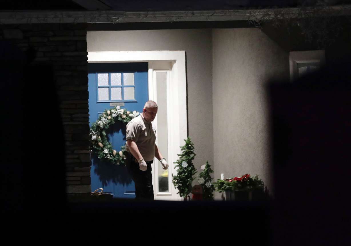 A law enforcement official stands at the front door of the Enoch, Iron County, home where eight family members were found shot to death Jan. 4.