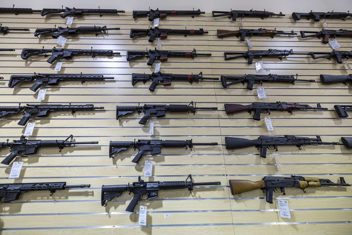 AR-15 and AK-47 rifles are displayed on a wall at Impact Guns in South Salt Lake on July 6, 2022.