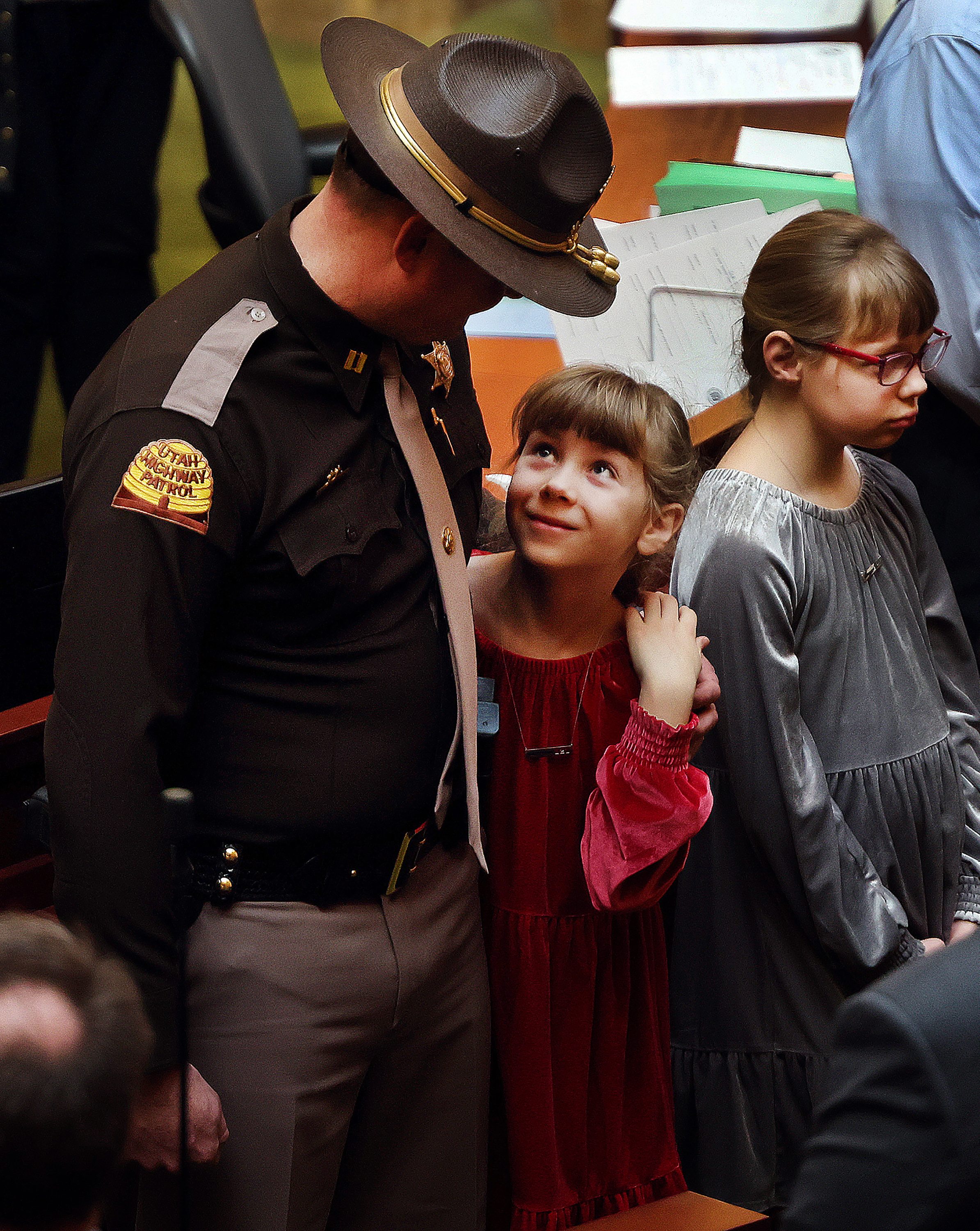 Maise Ward, a daughter of Sgt. Craig Ward, who died in 2022, looks up at Utah High Patrol Trooper Capt. Cody McCoy who was Sgt. Ward’s supervisor at the time of his death. The Utah House of Representatives honored families of first responders at the Capitol in Salt Lake City on Friday, Feb. 10, 2023.