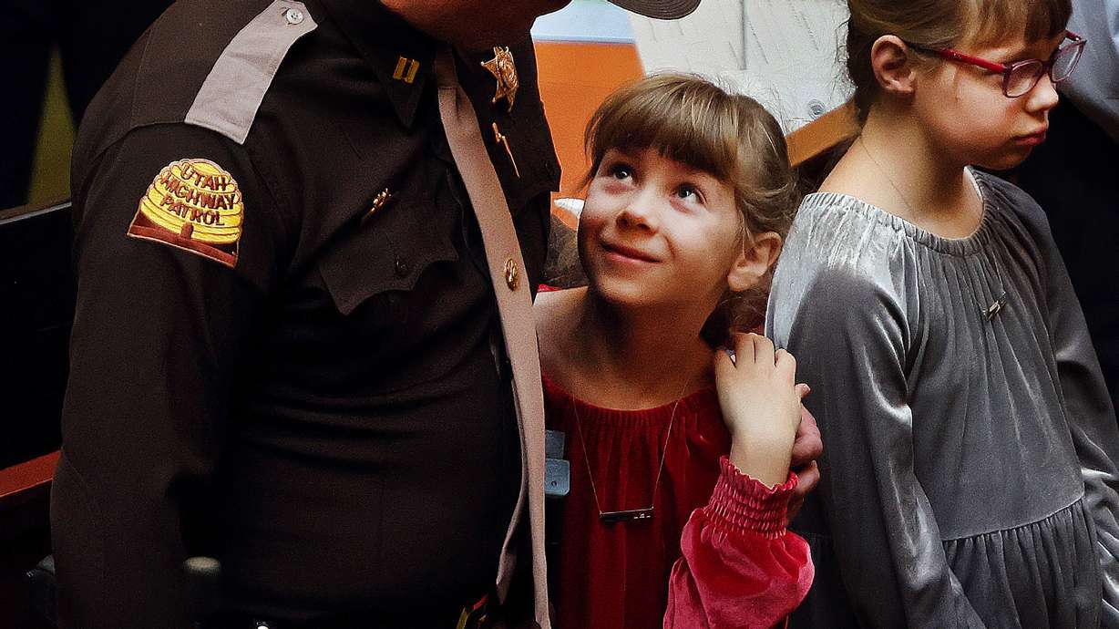 Maise Ward, a daughter of Sgt. Craig Ward, who died in 2022, looks up at Utah High Patrol Trooper Capt. Cody McCoy who was Sgt. Ward’s supervisor at the time of his death. The Utah House of Representatives honored families of first responders at the Capitol in Salt Lake City on Friday, Feb. 10, 2023.