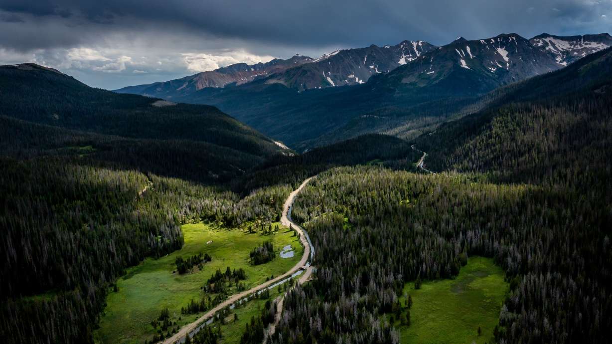 The headwater of the Colorado River, in the green meadow at left, is separated by a dirt road from the Grand Ditch on July 14, 2022. A program that aims to conserve Colorado River water in the four Upper Basin states is set to receive $125 million in new funds.