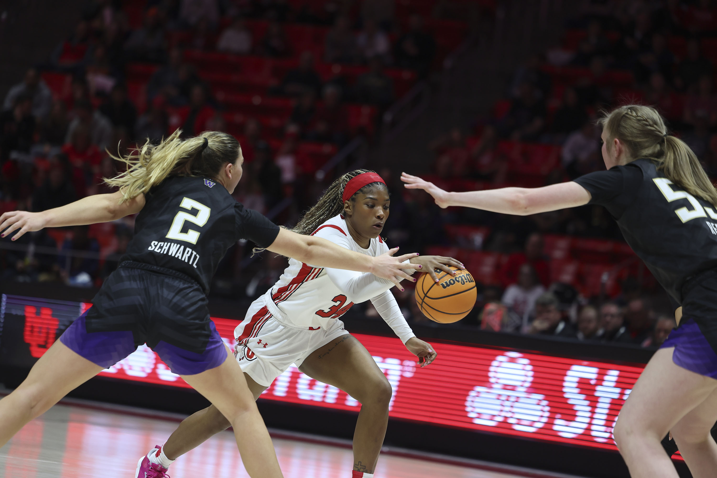 Utah Utes forward Dasia Young (34) dribbles into Washington Huskies forward Lauren Schwartz (2) and Washington Huskies center Darcy Rees (53) at the Jon M. Huntsman Center in Salt Lake City on Friday, Feb. 10, 2023.