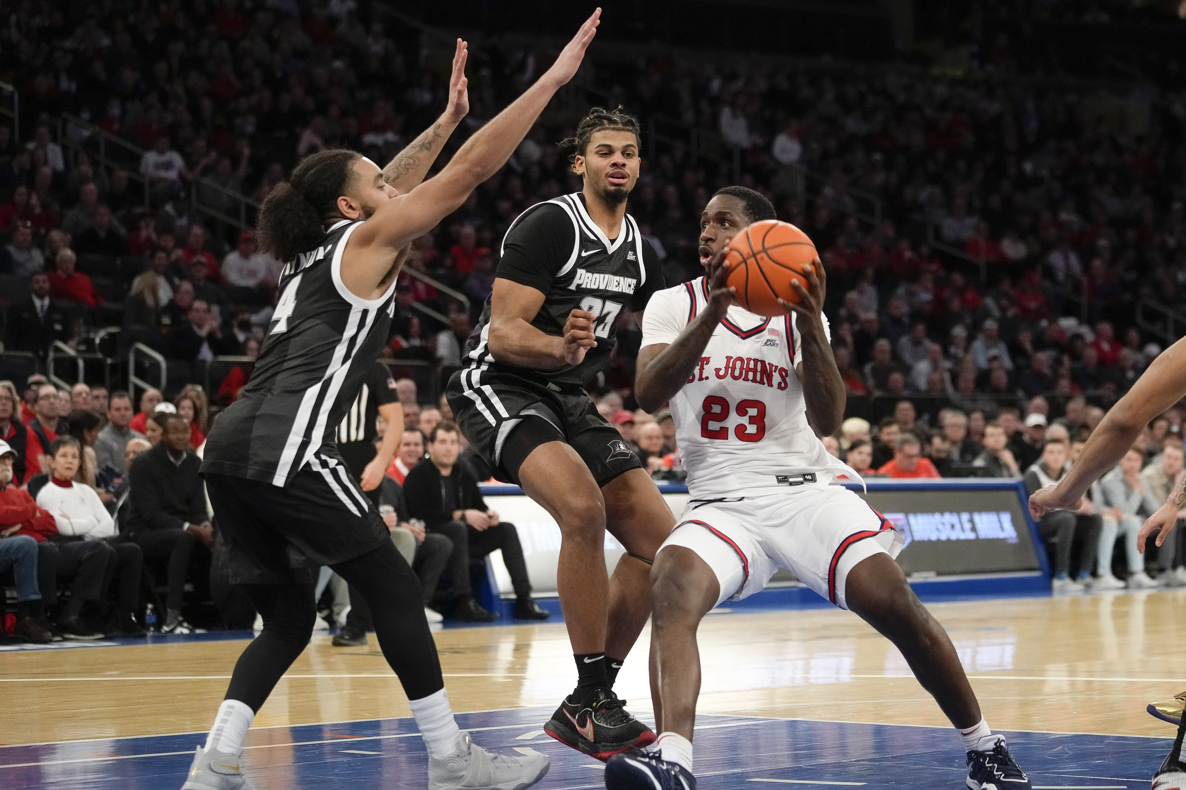 St. John's forward David Jones (23) drives to the basket as Providence guard Jared Bynum (4) and forward Bryce Hopkins (23) defend during the second half of an NCAA college basketball game, Saturday, Feb 11, 2023 in New York.