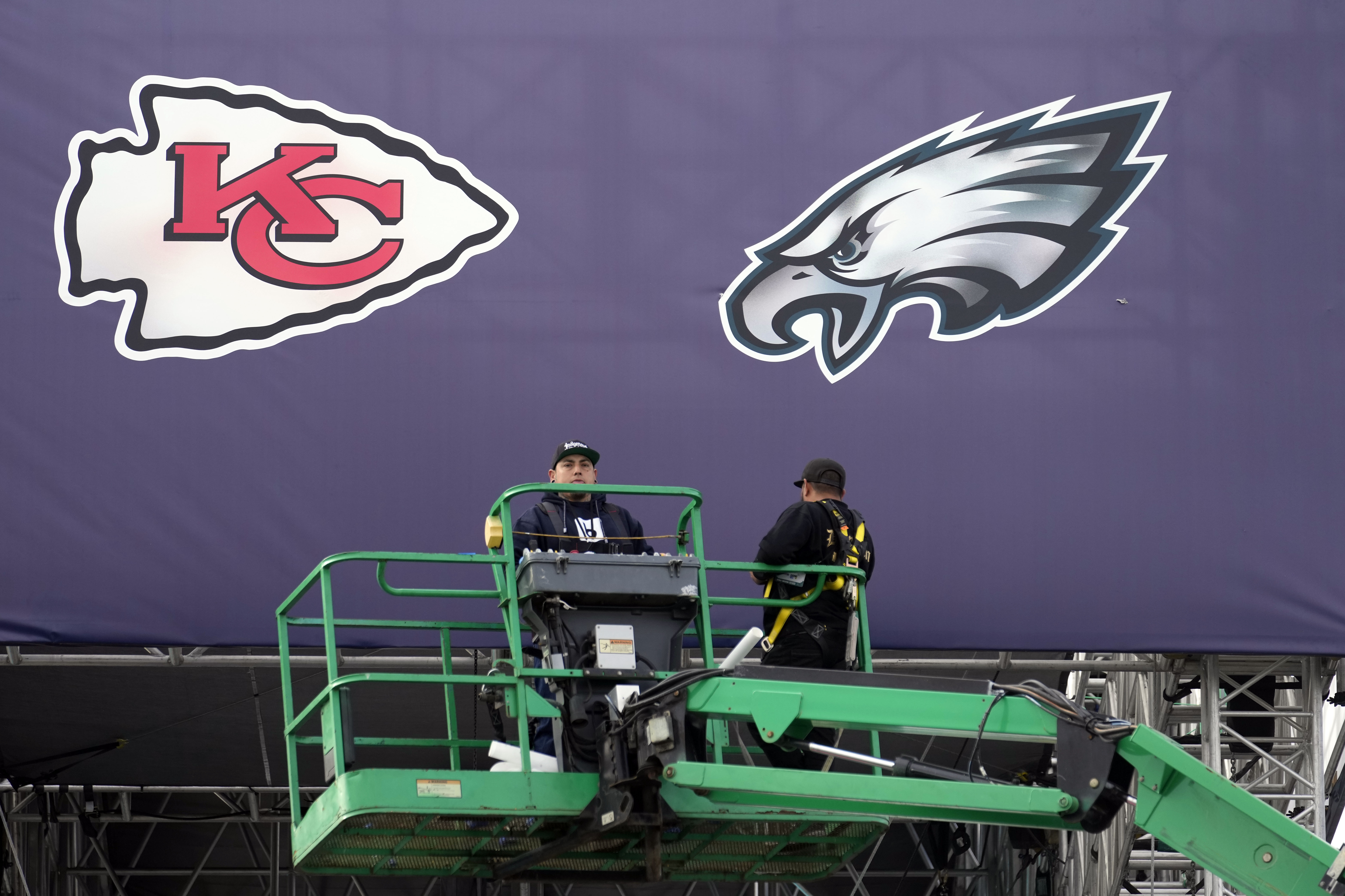 Works place team logos outside State Farm Stadium ahead of Super Bowl 57 NFL football game Saturday, Feb. 11, 2023, in Glendale, Ariz. The Kansas City Chiefs will play the Philadelphia Eagles on Sunday. 