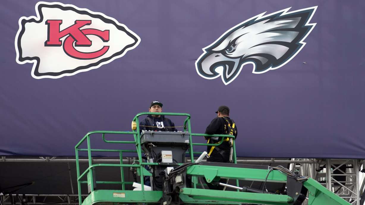 Works place team logos outside State Farm Stadium ahead of Super Bowl 57 NFL football game Saturday, Feb. 11, 2023, in Glendale, Ariz. The Kansas City Chiefs will play the Philadelphia Eagles on Sunday.