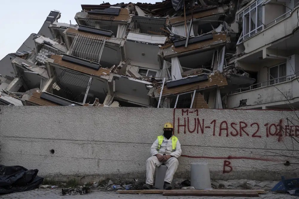 A rescue worker rests as others continue the search for victims of the earthquake in Antakya, Turkey, Saturday. Rescue crews on Saturday pulled more survivors, including entire families, from toppled buildings despite diminishing hopes as the death toll of the enormous quake that struck a border region of Turkey and Syria five days continued to rise.