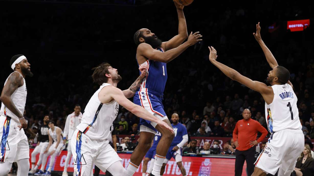 Philadelphia 76ers' James Harden, center, shoots against Brooklyn Nets' Joe Harris, second from left, and Mikal Bridges, right, during the second quarter of an NBA basketball game Saturday, Feb. 11, 2023, in New York.