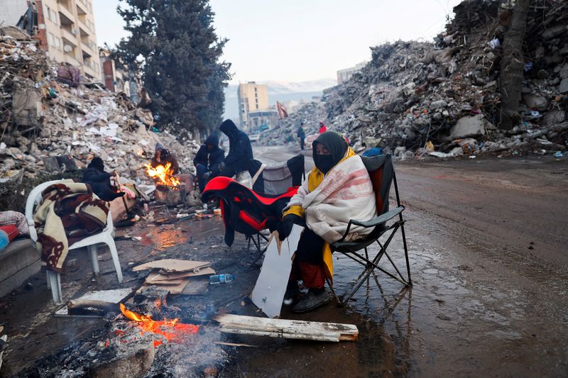 A person keeps warm by a fire as the search for survivors continues in the aftermath of a deadly earthquake in Kahramanmaras, Turkey, Monday.