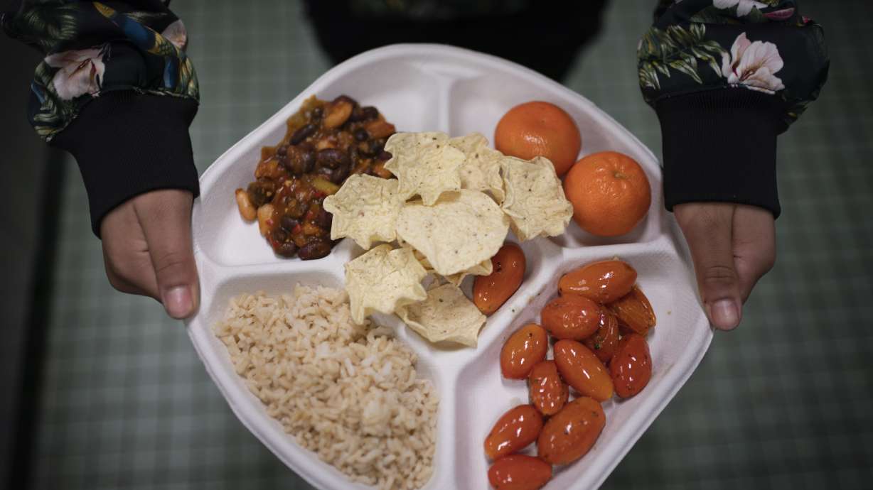 A seventh grader carries her plate which consists of three bean chili, rice, mandarins and cherry tomatoes and baked chips during her lunch break Saturday in Brooklyn. A 2010 federal law that boosted nutrition standards for school meals may have helped curb obesity among America’s children — even teenagers who can buy their own snacks, according to a new study.