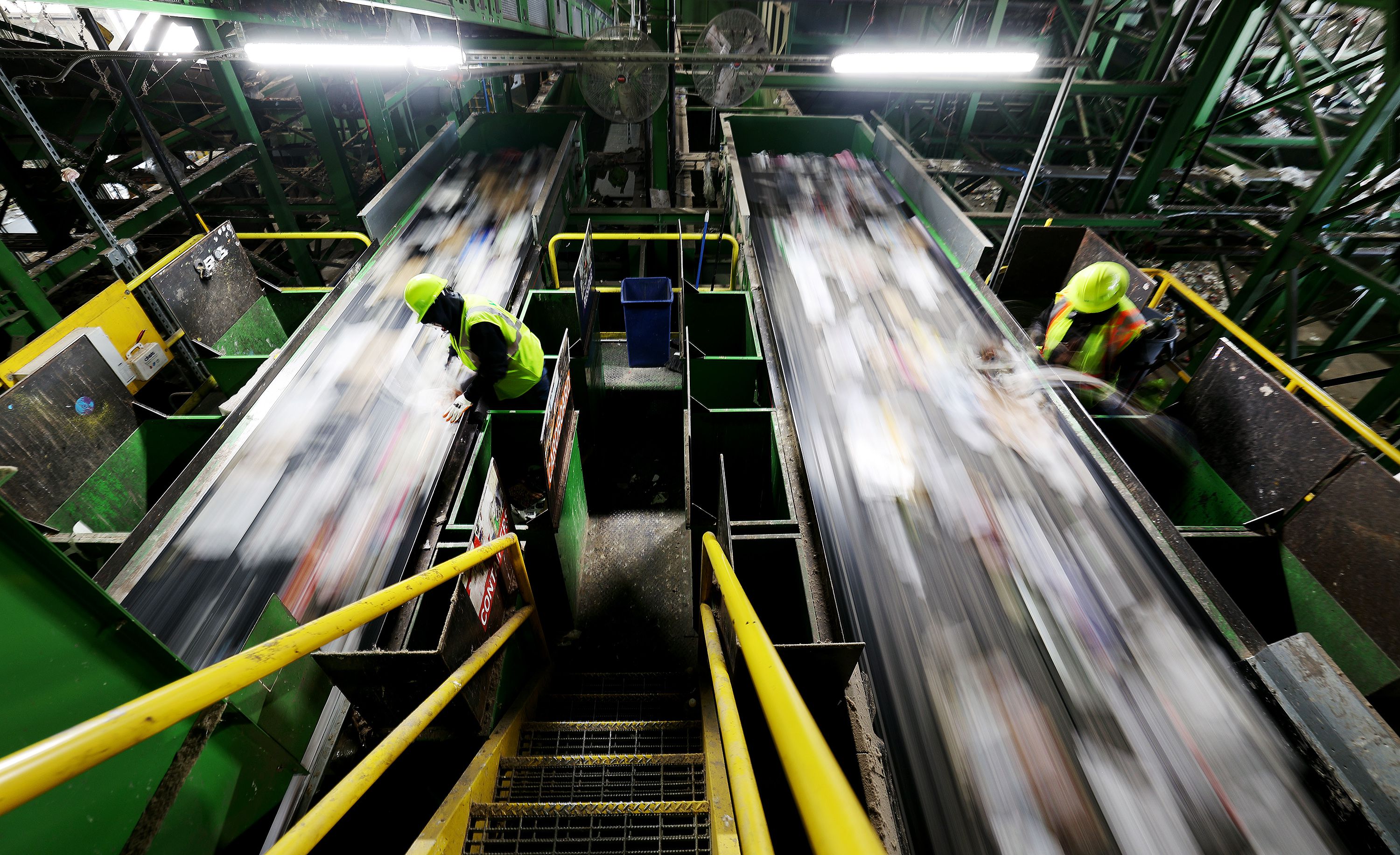 Workers hand-sort items from conveyors at the Waste Management sorting center in Salt Lake City on Monday.