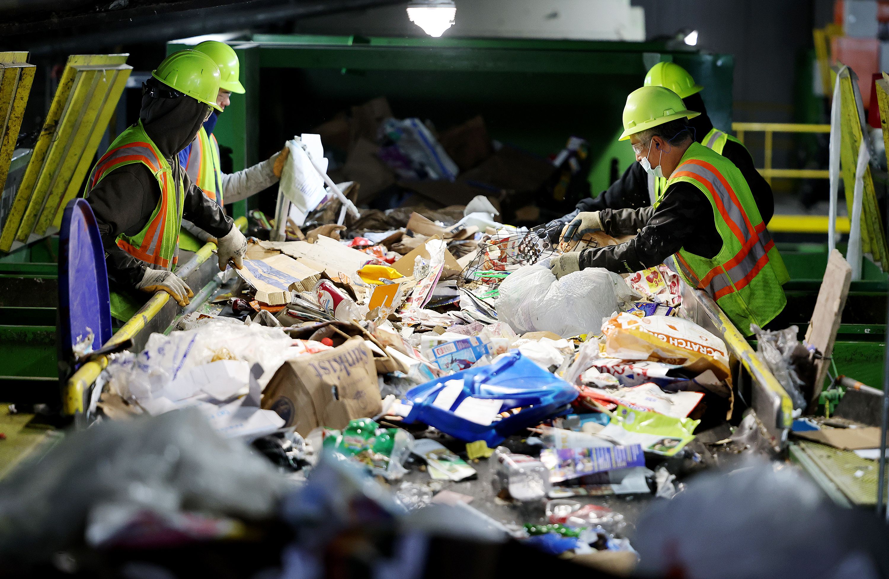 Workers hand-sort items from conveyors at the Waste Management sorting center in Salt Lake City on Monday.
