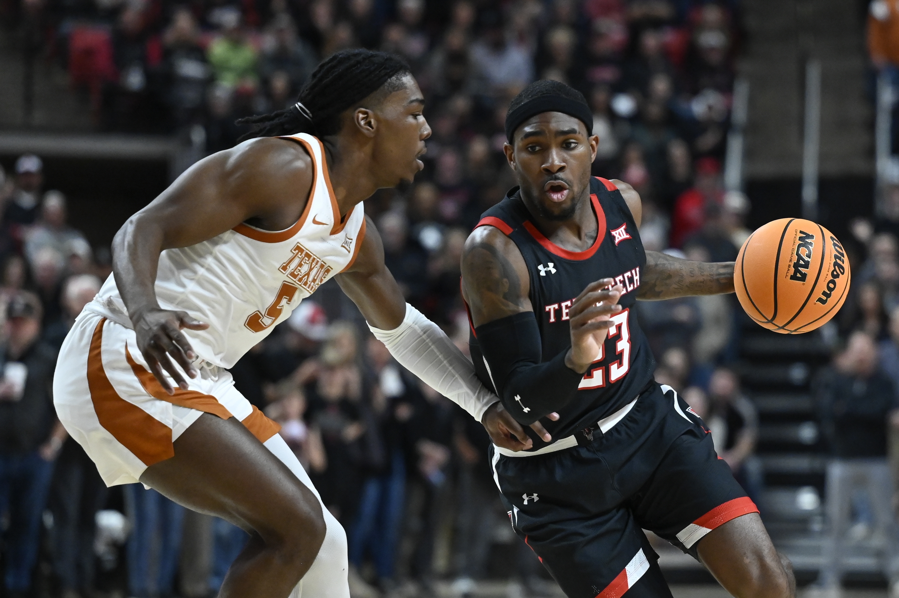 Texas Tech guard De'Vion Harmon (23) brings the ball upcourt against Texas guard Marcus Carr (5) during the first half of an NCAA college basketball game, Monday, Feb. 13, 2023, in Lubbock, Texas. 