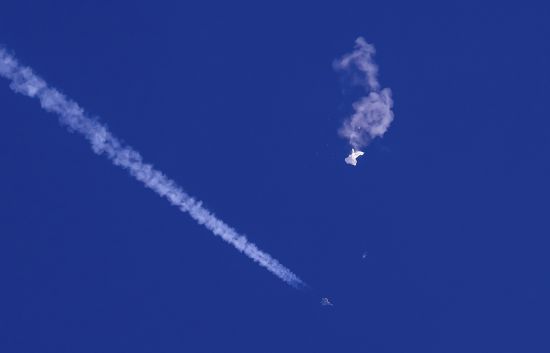 The remnants of a large balloon drift above the Atlantic Ocean, just off the coast of South Carolina, with a fighter jet and its contrail seen below it, Feb. 4. A missile fired on Feb. 5 by a U.S. F-22 off the Carolina coast ended the days-long flight of what the Biden administration says was a surveillance operation that took the Chinese balloon near U.S. military sites.