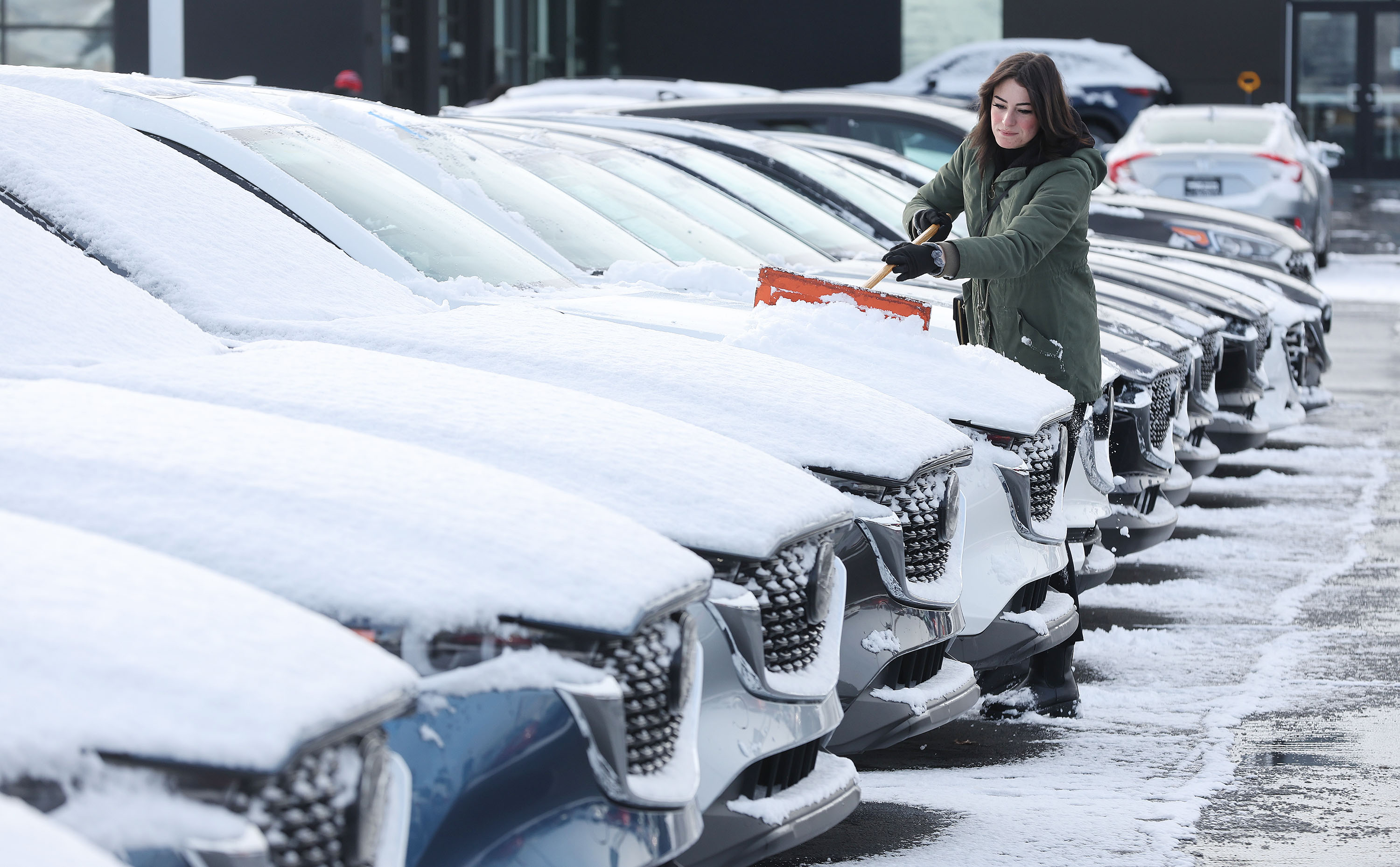Lily Foutz clears off cars for sale at Tim Dahle Mazda in Murray on Tuesday.