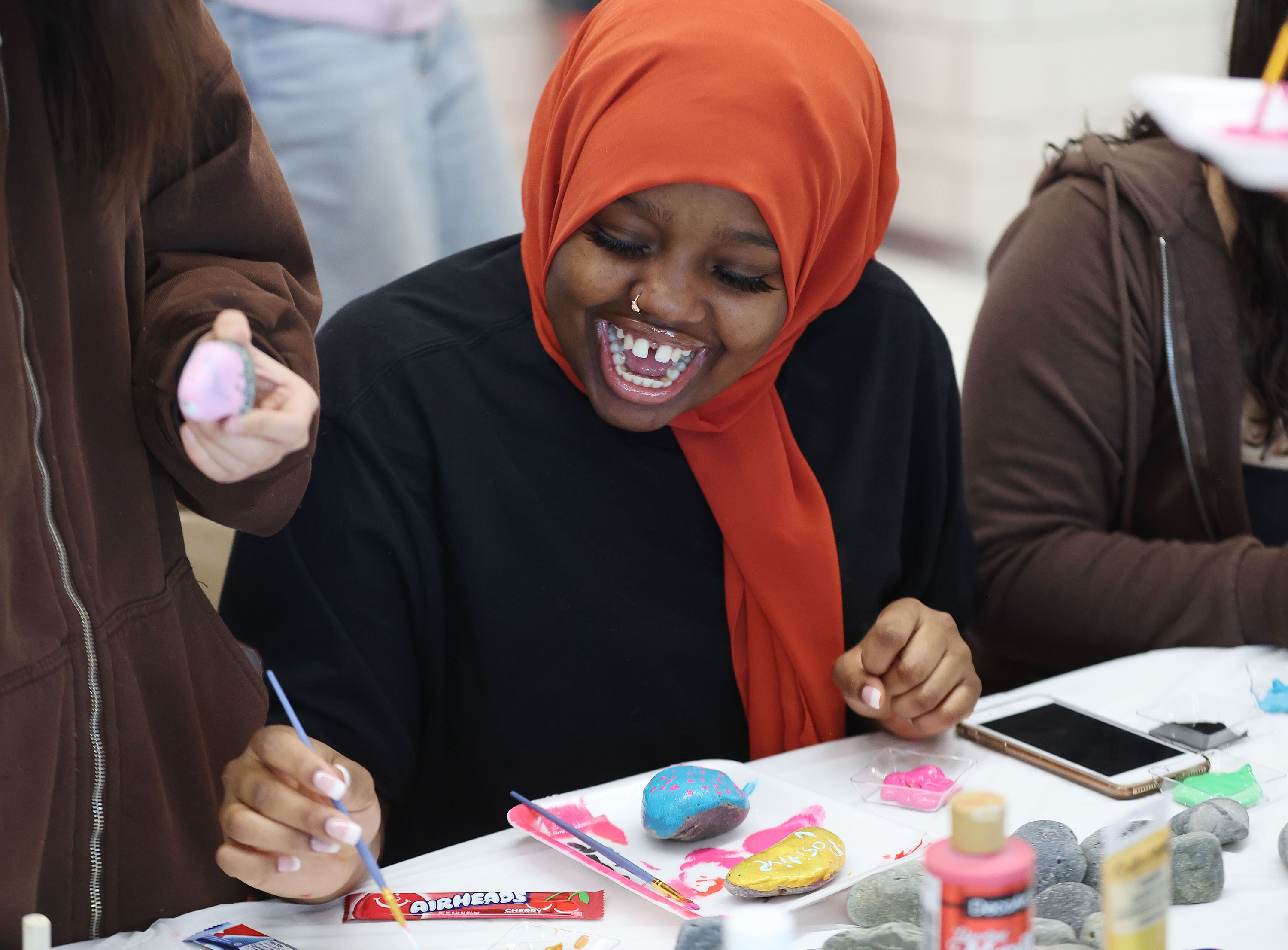 East High School student Fadumo Aden has fun painting a rock that has a kind message on it in Salt Lake City on Tuesday. Students participated in the community outreach project focused on kindness.