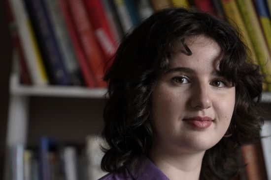 Virginia Faust, of Somerville, Mass., poses in her home, Monday. Faust has health insurance, but she still fell several thousand dollars into debt in 2021 when a mental health emergency required a weeklong stay in the hospital.