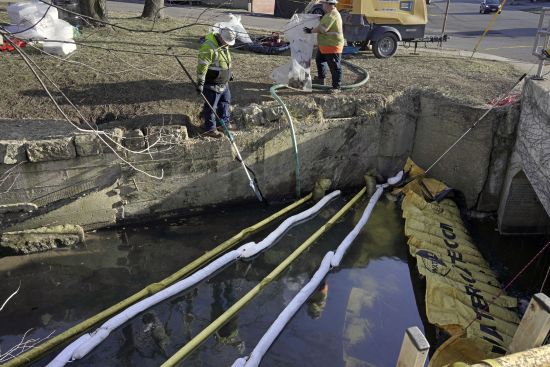 Booms are placed in a stream that flows through the center of East Palestine, Ohio, as the cleanup continues following the derailment of a Norfolk Southern freight train over a week ago, Wednesday.