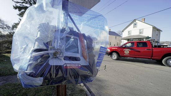 An air quality monitoring device hangs on a stop sign in East Palestine, Ohio, as the cleanup continues after the derailment of a Norfolk Southern freight train over a week ago, Wednesday.