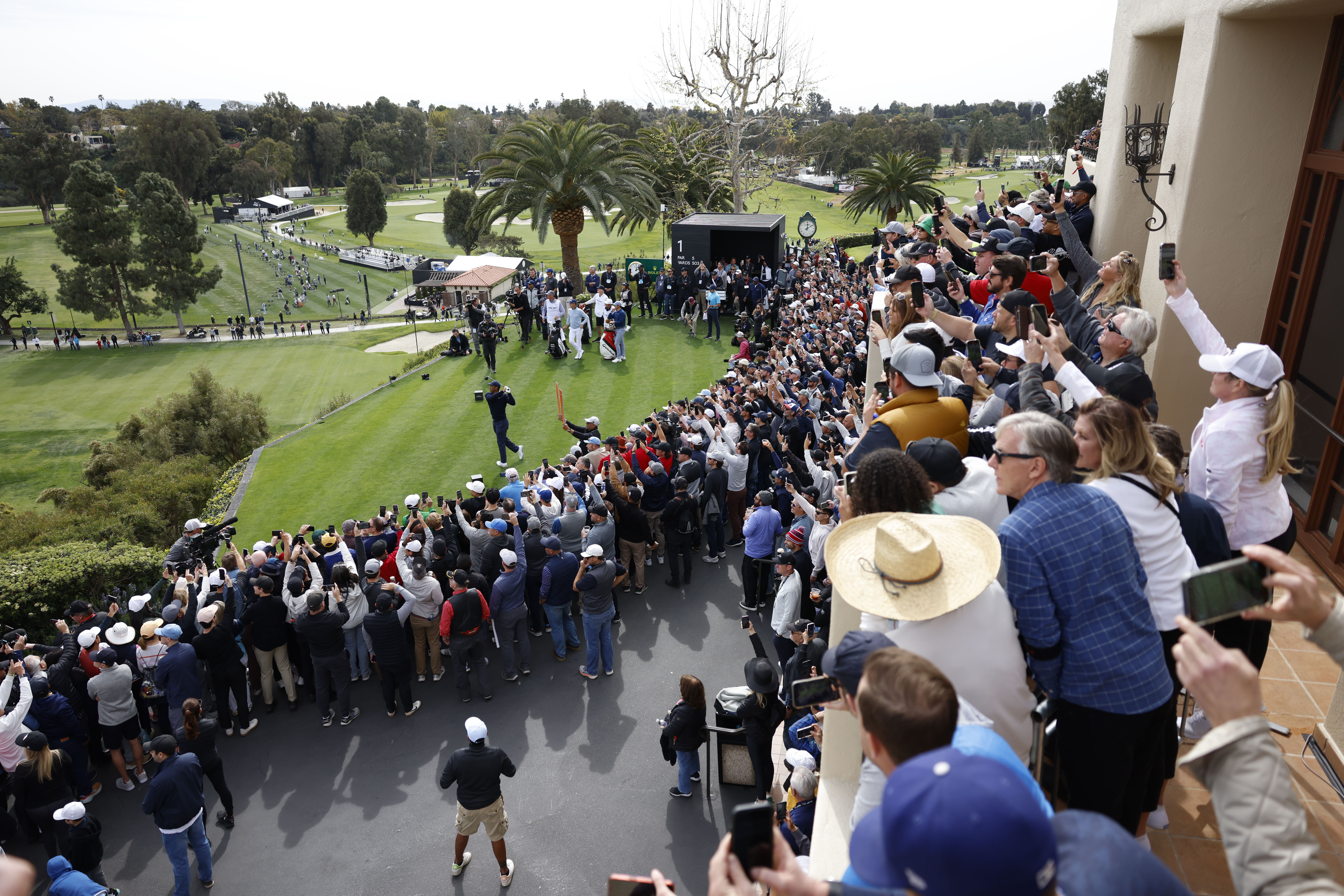 The gallery watches Tiger Woods, bottom left, as hits from the first tee during the first round of the Genesis Invitational golf tournament at Riviera Country Club, Thursday, Feb. 16, 2023, in the Pacific Palisades area of Los Angeles. 