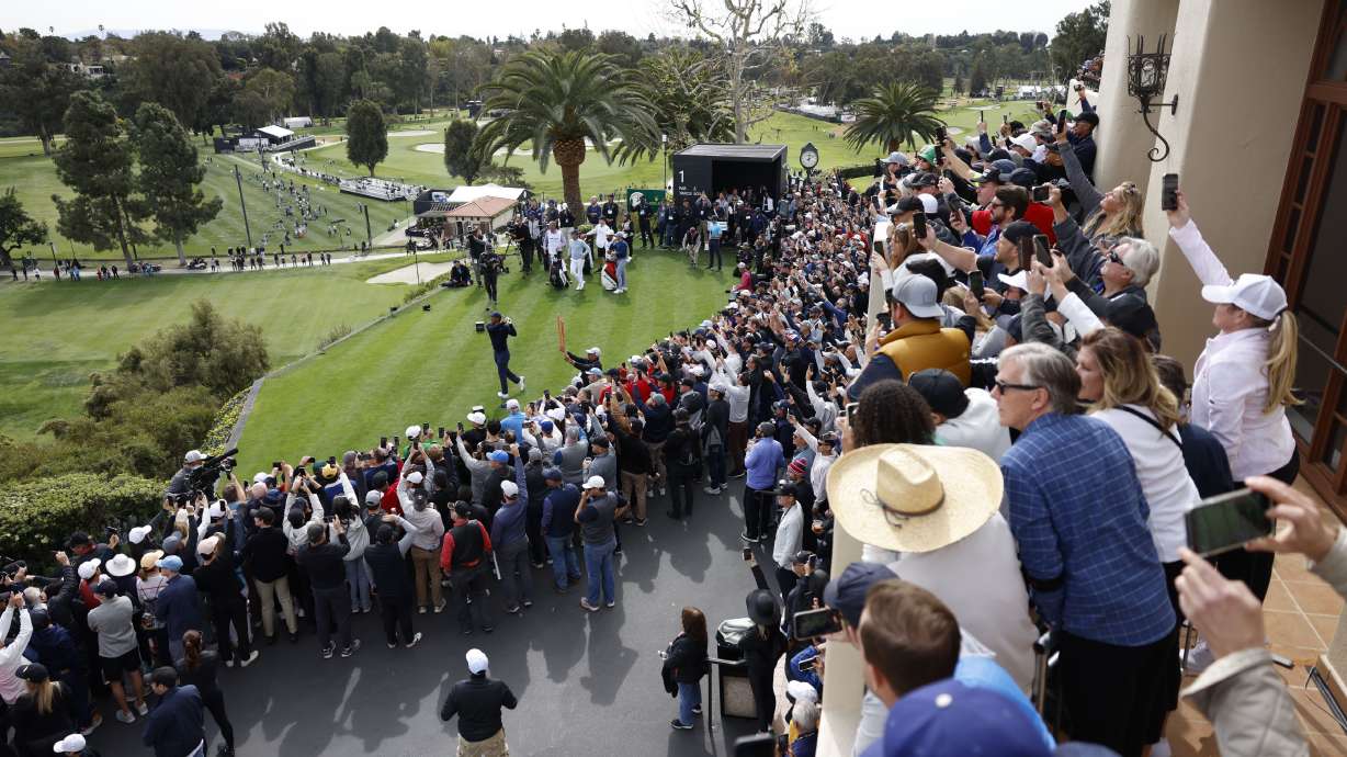The gallery watches Tiger Woods, bottom left, as hits from the first tee during the first round of the Genesis Invitational golf tournament at Riviera Country Club, Thursday, Feb. 16, 2023, in the Pacific Palisades area of Los Angeles.