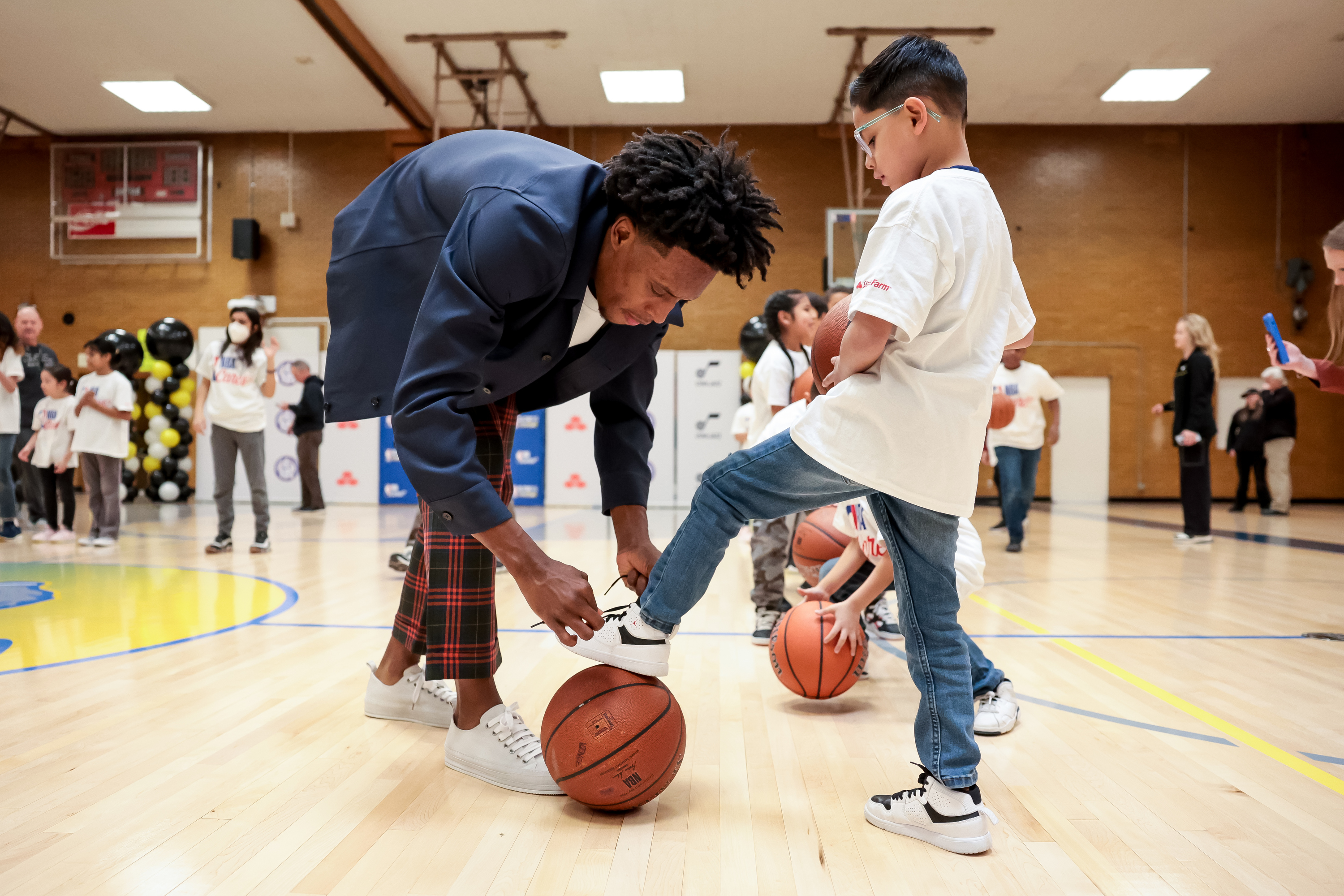 Utah Jazz point guard Collin Sexton helps Ivan Camacho, 6, tie his shoe before shooting hoops during an event at Lincoln Elementary in South Salt Lake on Thursday, Feb. 16, 2023. The event unveiled a renovated gym and a new STEM classroom donated by NBA Cares and partners.