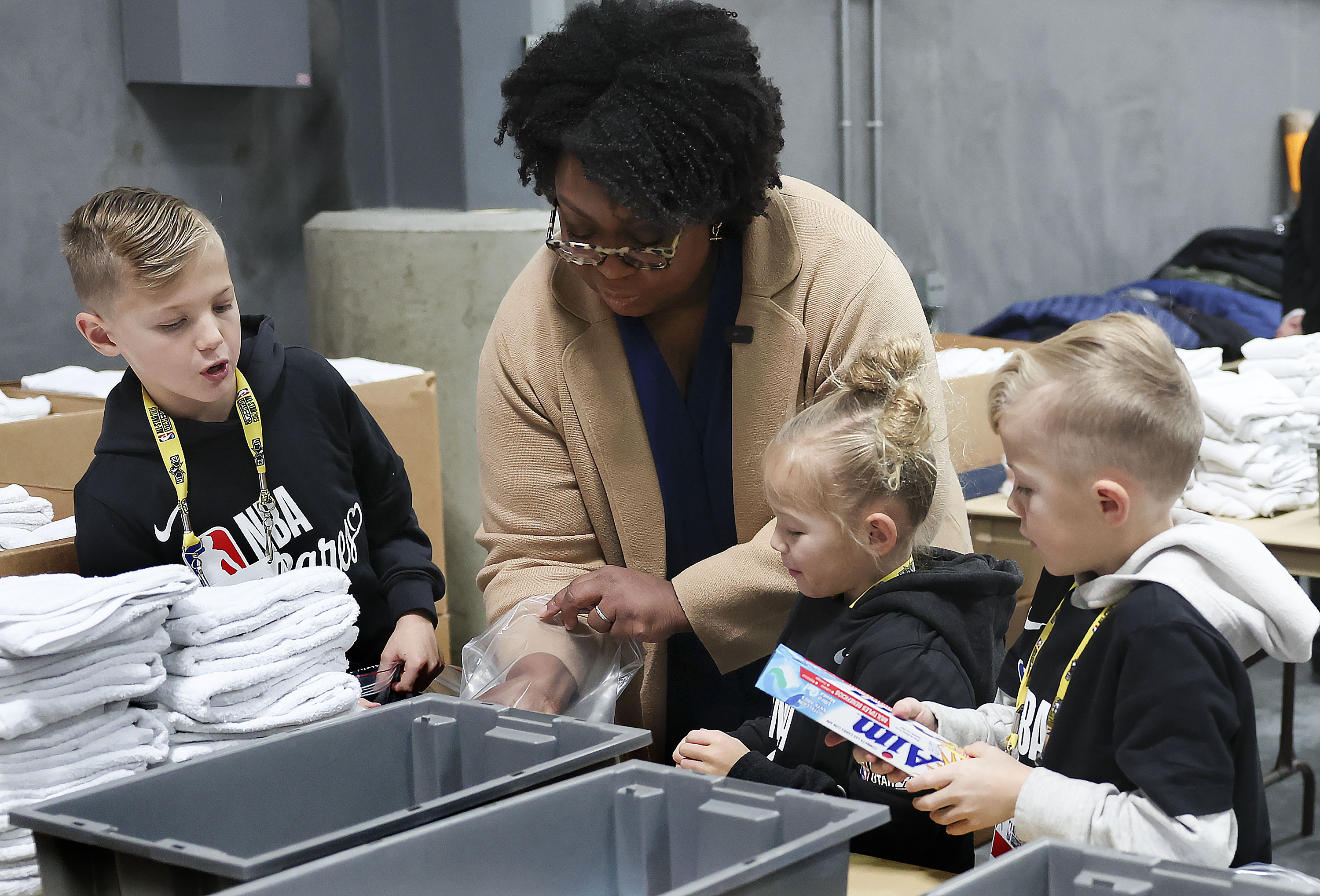Sister Tracy Y. Browning, second counselor in the Primary general presidency for The Church of Jesus Christ of Latter-day Saints, packs up toiletry kits with Jet, Violet and Jude Smith at the Bishops' Central Storehouse in Salt Lake City on Friday as part of the NBA Cares All-Star Day of Service.