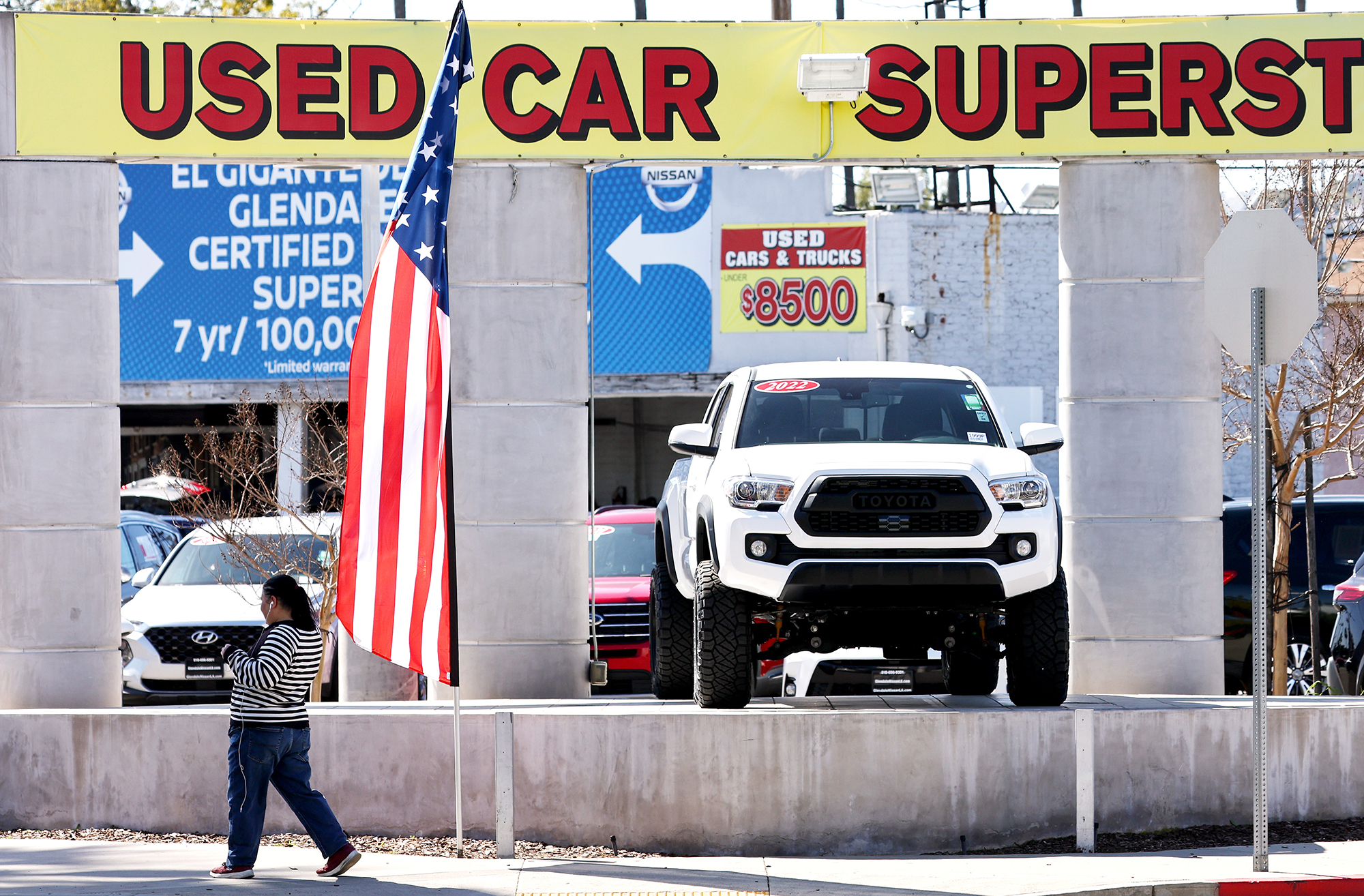 A pedestrian walks past a used car lot on Feb. 15 in Glendale, California. The price of used cars has been falling steadily, and steeply, for much of the last year but may now be on the rise.