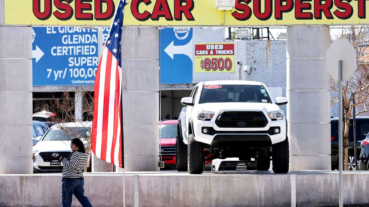 A pedestrian walks past a used car lot on Feb. 15 in Glendale, California. The price of used cars has been falling steadily, and steeply, for much of the last year but may now be on the rise.