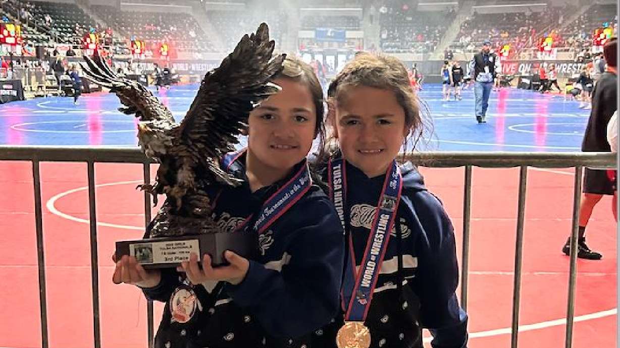 Lina Nau Rarick, 7, of Saratoga Springs, holds a national championship wrestling trophy after losing a final match to her twin sister, Losa Nau Rarick, earlier this year. Losa, who won last year, gave up against her sister to give Line a chance to win the title.