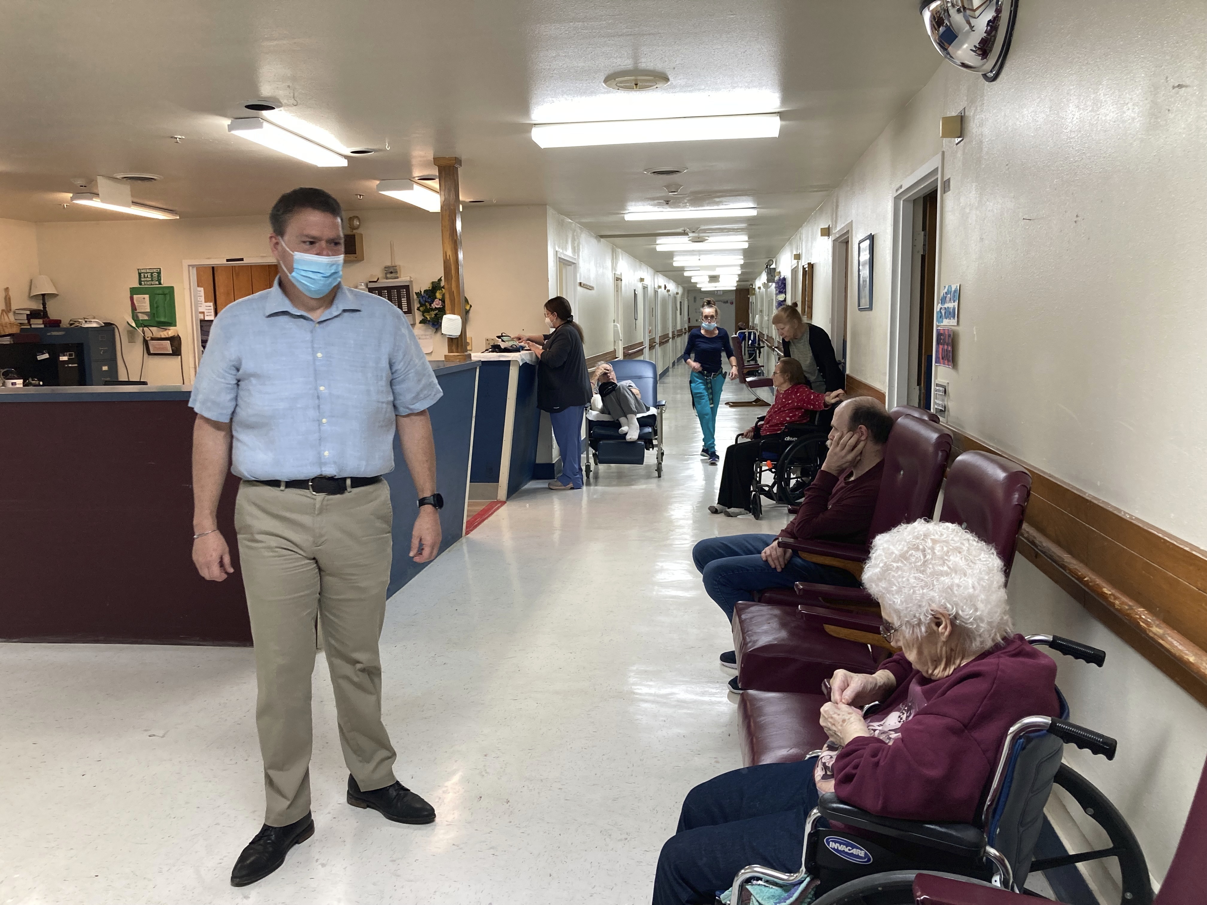 Tim Corbin, left, the administrator of Truman Lake Manor, passes through the hallway of the nursing home on Feb. 14, in Lowry, Mo. Corbin believes it's time for the federal vaccination requirement for health care workers to end.