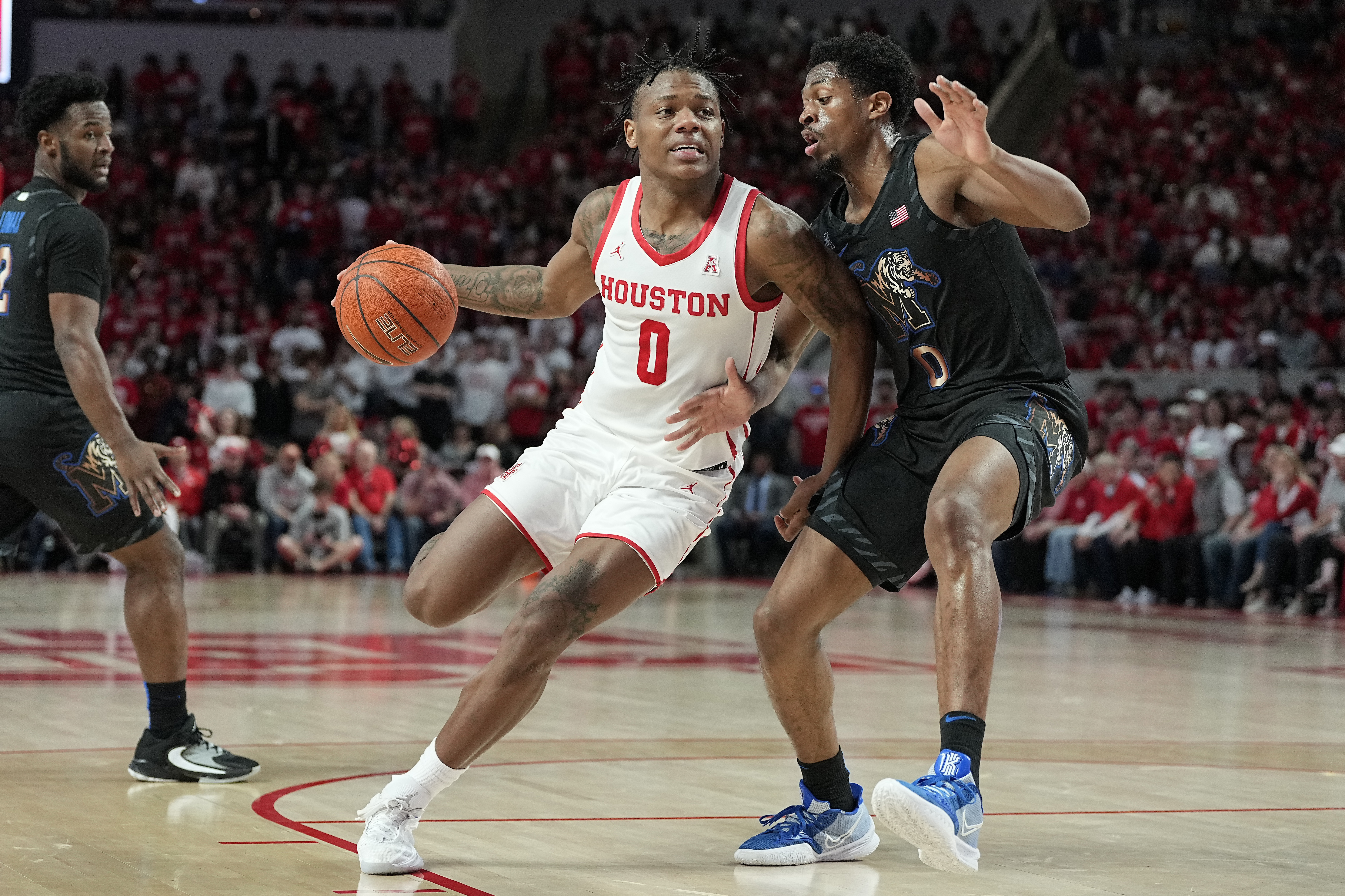 Houston guard Marcus Sasser (0) drives the lane against Memphis guard Elijah McCadden, right, during the second half of an NCAA college basketball game, Sunday, Feb. 19, 2023, in Houston. 