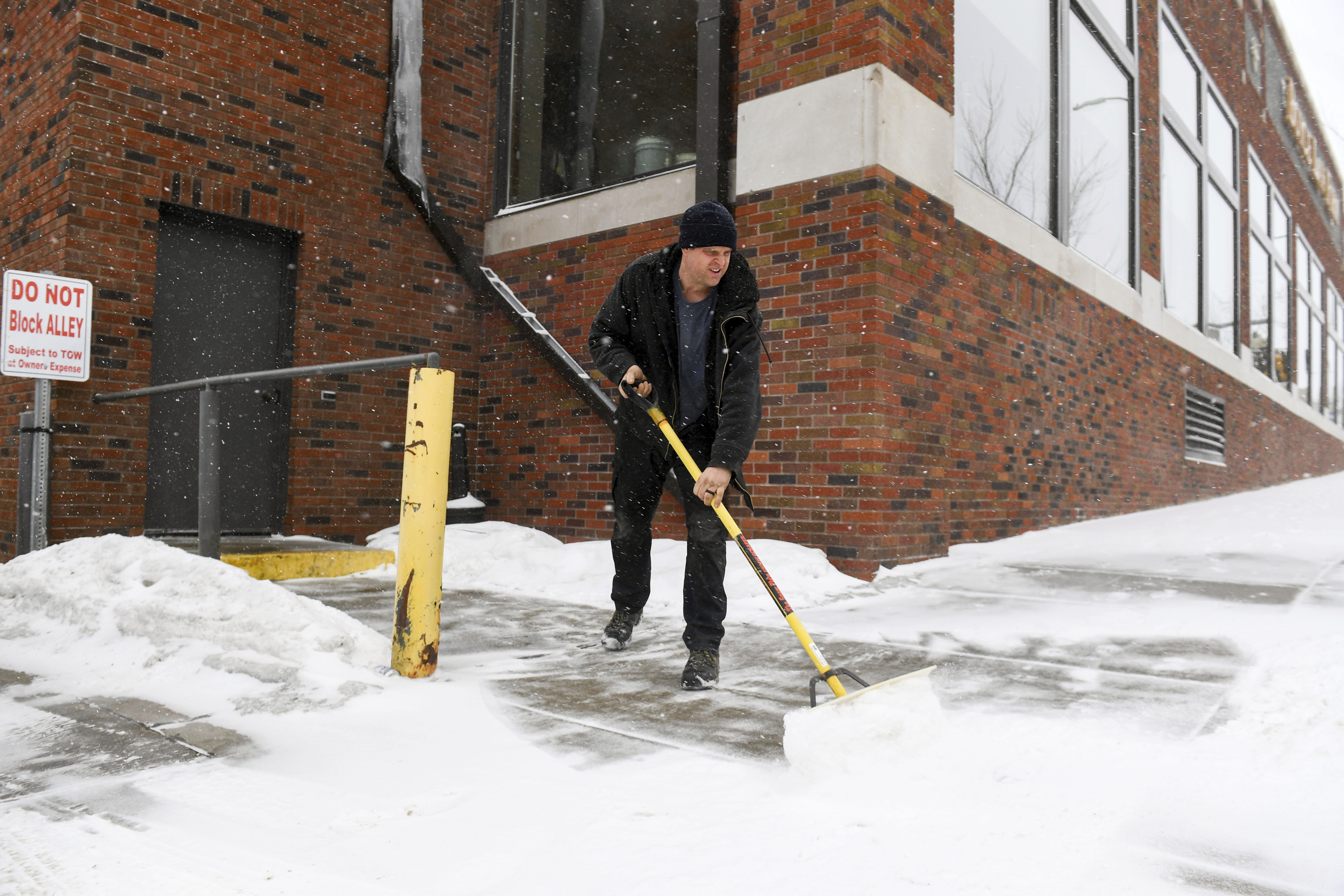 David Smith shovels the sidewalk as the first snow falls ahead of a winter storm on Tuesday in Sioux Falls, S.D. A wide swath of the Upper Midwest is bracing for a historic winter storm. 
