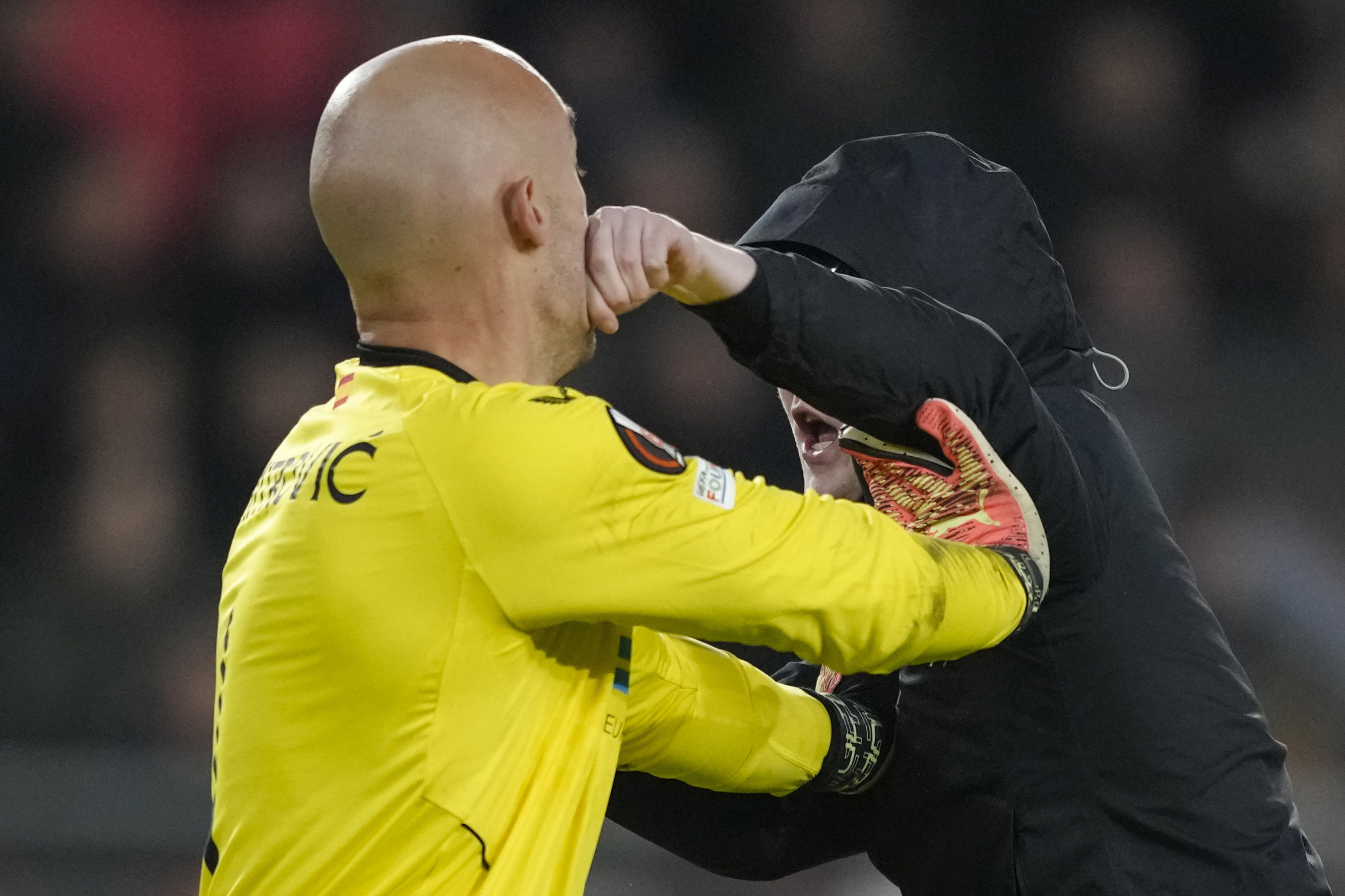 A PSV supporter punches Sevilla's goalkeeper Marko Dmitrovic in the face during the Europa League playoff second leg soccer match between PSV and Sevilla at the Philips stadium in Eindhoven, Netherlands, Thursday, Feb. 23, 2023. Sevilla won 3-2 on aggregate. 