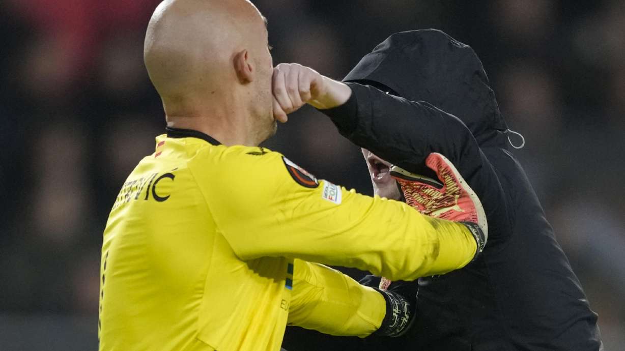 A PSV supporter punches Sevilla's goalkeeper Marko Dmitrovic in the face during the Europa League playoff second leg soccer match between PSV and Sevilla at the Philips stadium in Eindhoven, Netherlands, Thursday, Feb. 23, 2023. Sevilla won 3-2 on aggregate.