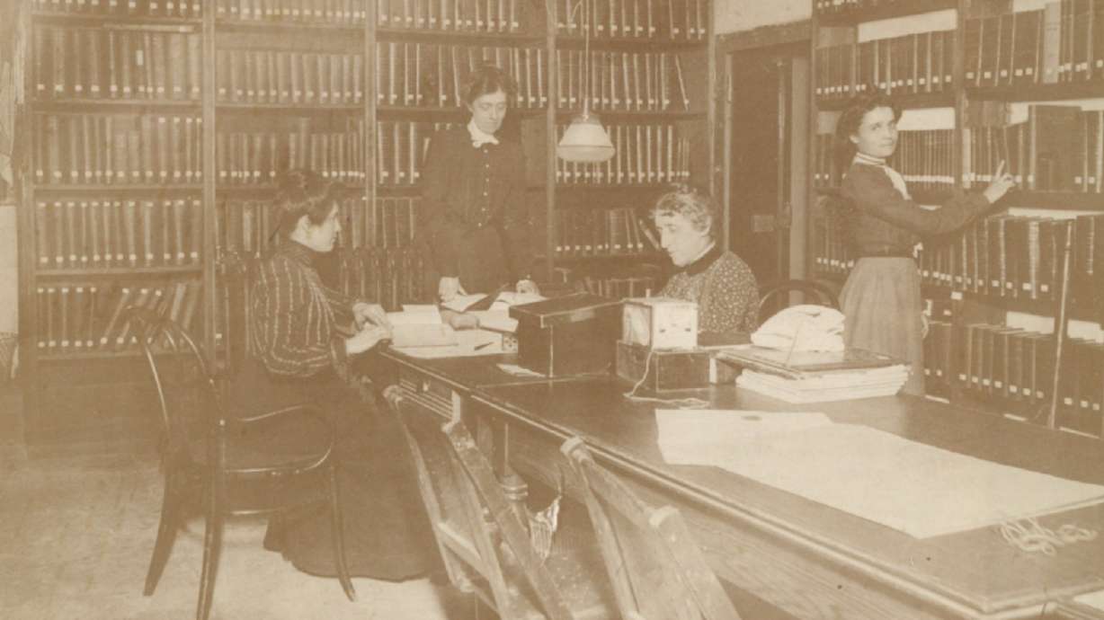 An undated photo of Joanna Sprague (standing, facing the table) and Annie Chapman (sitting, facing the left) inside the first Salt Lake City Public Library. The library first opened 125 years ago this month. Chapman and Sprague served as the first two head librarians in the city's public library system.