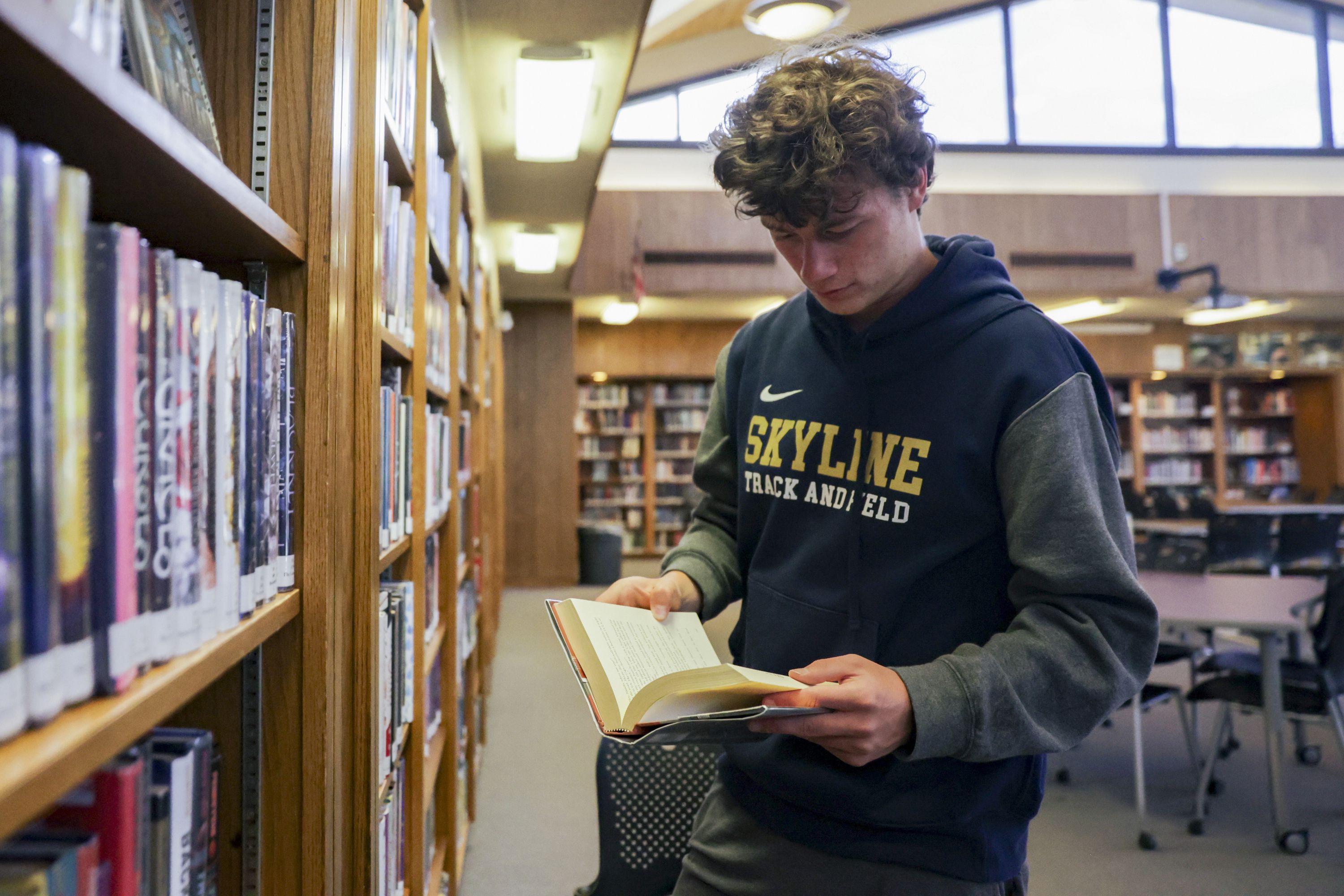 Henry Christiansen, a senior at Skyline High School, reads a book at the library at the school.