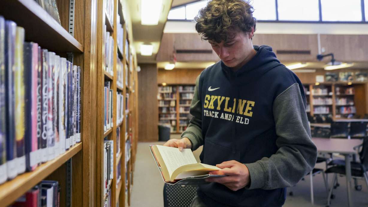 Henry Christiansen, a senior at Skyline High School, reads a book at the library at the school.