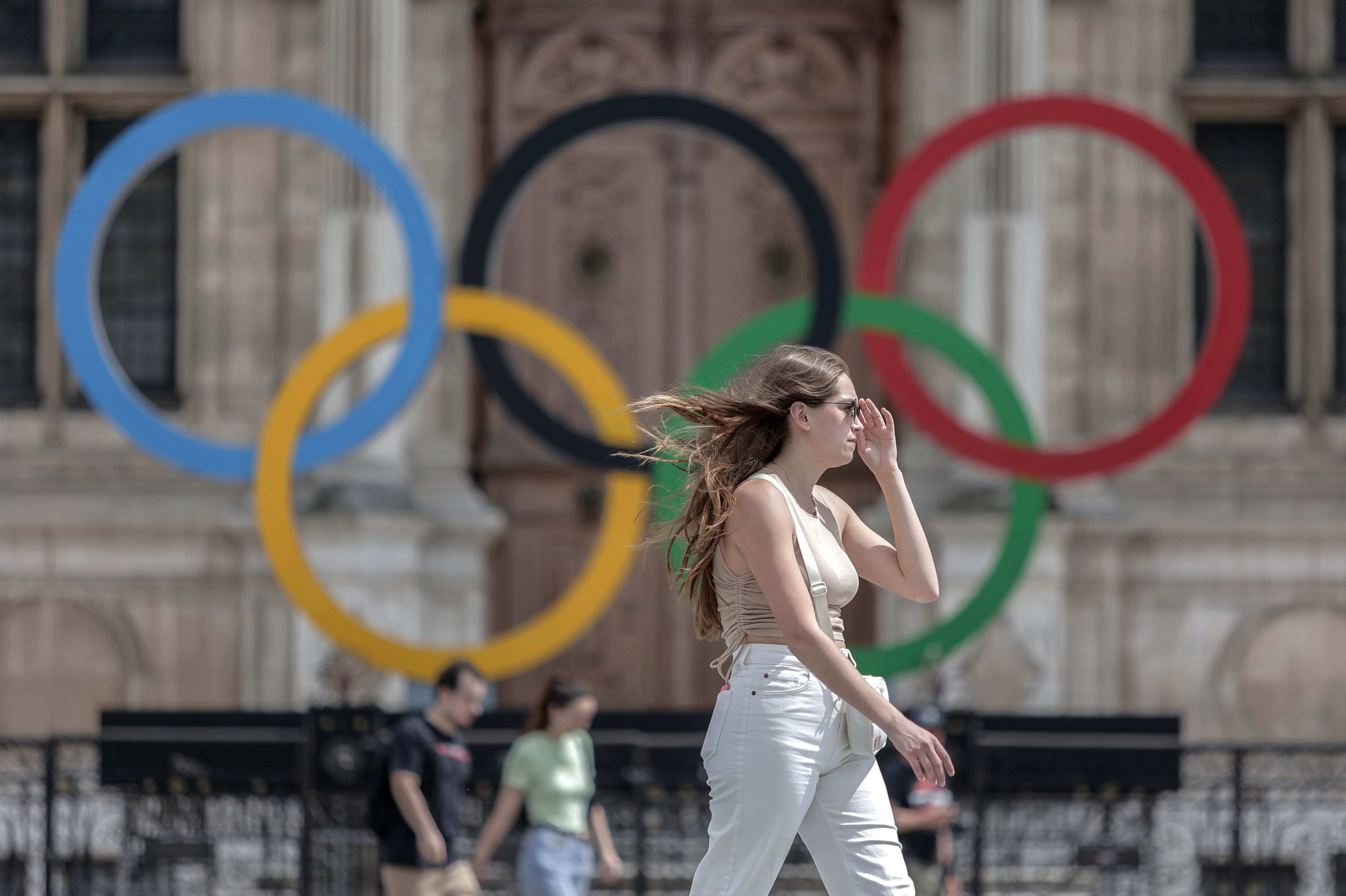 A woman passes by the Olympic rings at the City Hall in Paris, July 25, 2022.