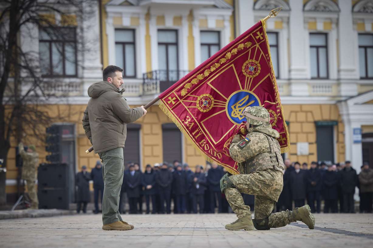 Ukrainian President Volodymyr Zelenskyy, left, holds the flag of a military unit as an officer kisses it, during a commemorative event on the occasion of the Russia-Ukraine war's one-year anniversary in Kyiv, Ukraine, Friday.