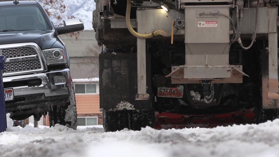 Vehicles are parked along the street as a snowplow moves through in West Jordan Thursday. Police warn residents to get parked cars off the street so plows can clear the snow.