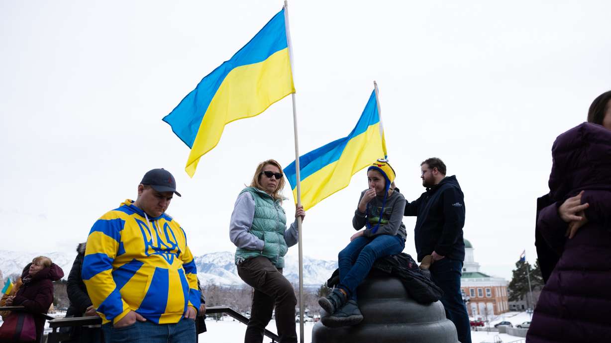 Zlata Yurchenko, Lena Yurchenko, and Jacob Richardson, middle to right, stand with Ukrainian flags during a rally commemorating the one year anniversary of the Ukraine-Russia war, at the Capitol in Salt Lake City on Saturday.