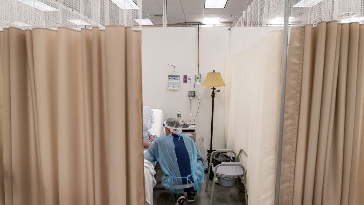 A physical therapist works with a patient at a field hospital in Cranston, R.I, Dec. 14, 2020. Roughly 84 million people are covered by Medicaid, but as many as 14 million people could lose access to that coverage.