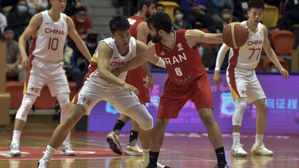 In this photo released by Xinhua News Agency, Behnam Yakhchali of Iran, right, tries to get past Zhao Rui of China during the Group F match between China and Iran in the FIBA Basketball World Cup Asian Qualifiers in Hong Kong, Sunday, Feb. 26, 2023. Iran has clinched Asia's final qualifying spot for the basketball World Cup despite losing its final playoff game 86-74 to China on Sunday.