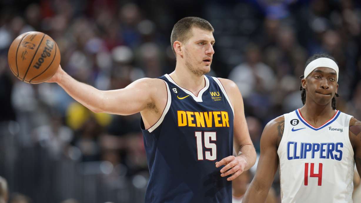 Denver Nuggets center Nikola Jokic holds on to the ball as time runs out in overtime of an NBA basketball game as Los Angeles Clippers guard Terance Mann reacts Sunday, Feb. 26, 2023, in Denver.