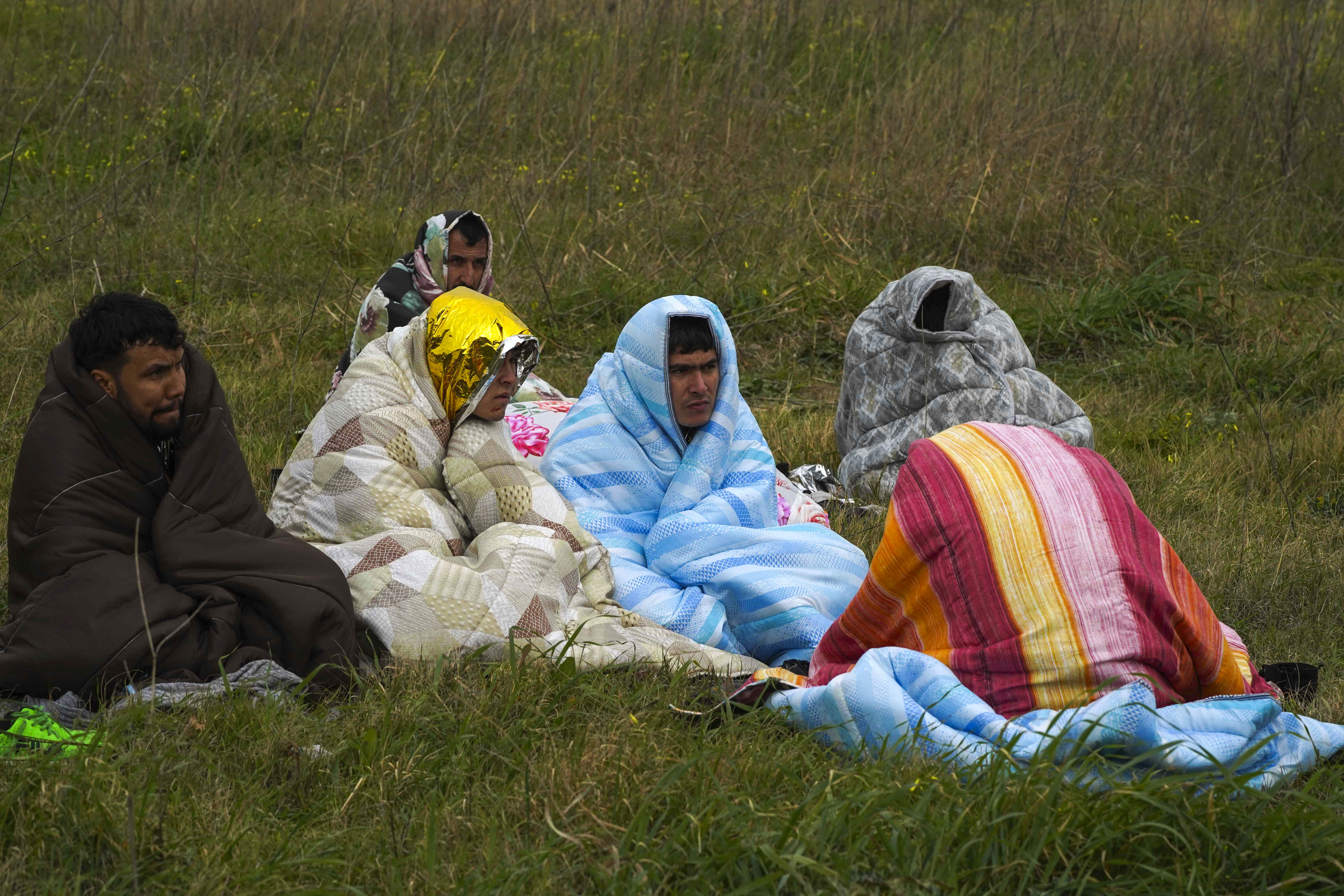 Rescued migrants sit covered in blankets at a beach near Cutro, southern Italy, Sunday. Rescue officials say an undetermined number of migrants have died and dozens have been rescued after their boat broke apart off southern Italy.