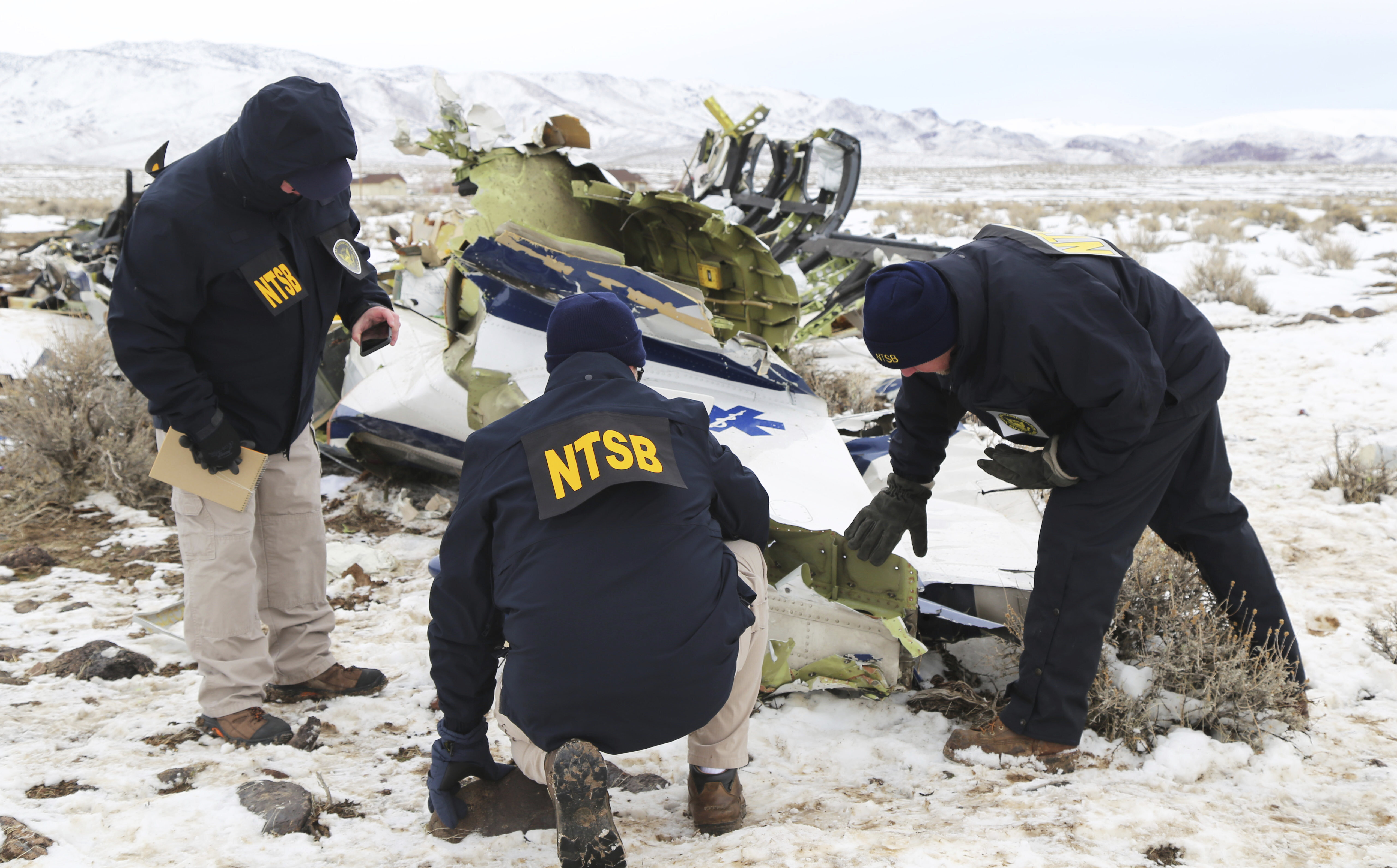 This photo provided by The National Transportation Safety Board shows NTSB investigators documenting the wreckage of a Pilatus PC-12 airplane at the crash site in Dayton, Nev., on Sunday, Feb. 26, 2023. A medical transport flight that crashed in a mountainous area in northern Nevada, killing five all five people aboard the plane including a patient, apparently broke apart before hitting the ground, authorities said Sunday. 