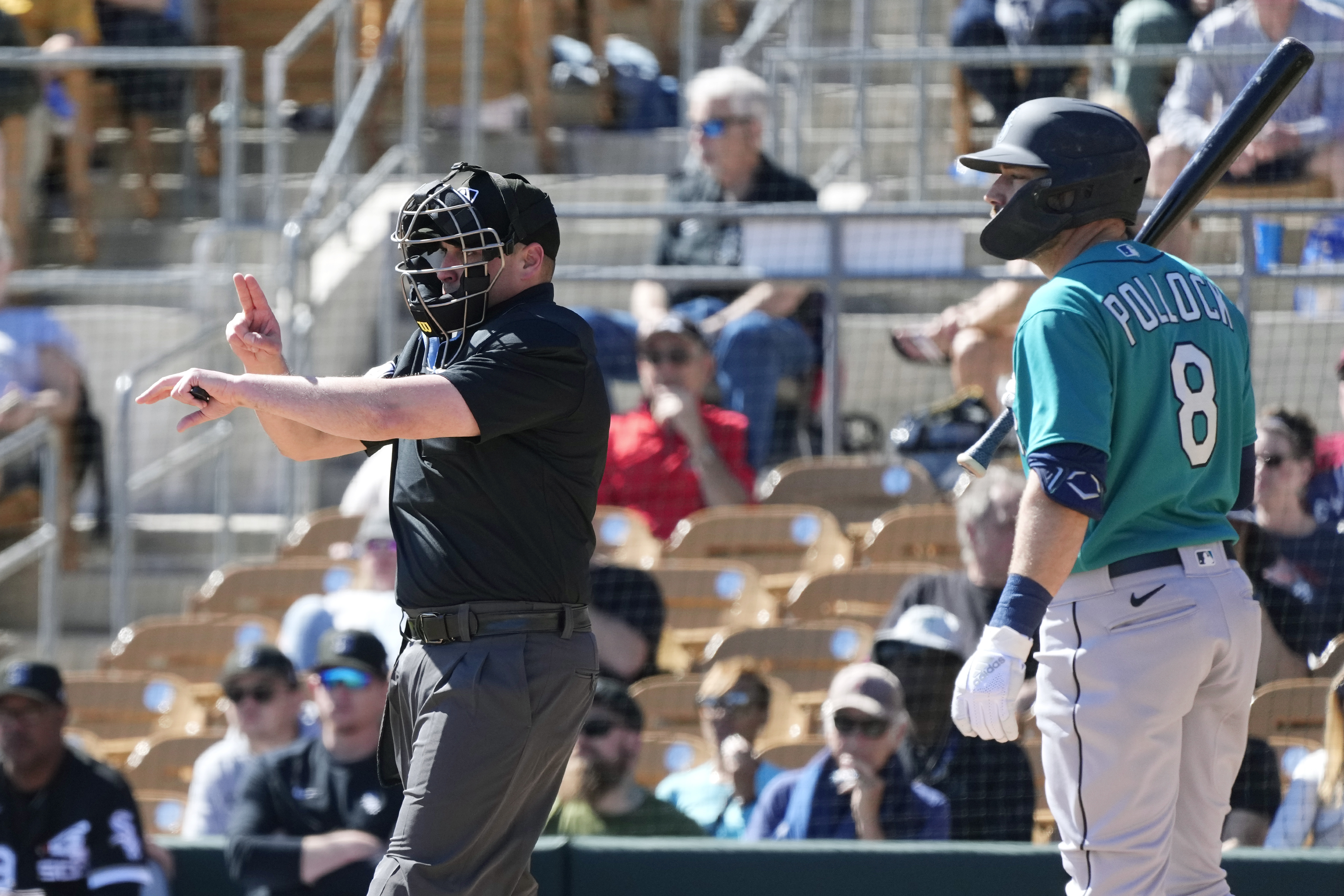 Home plate umpire Paul Clemons, left, calls a pitching clock violation against Chicago White Sox relief pitcher Reynaldo Lopez as Seattle Mariners' AJ Pollock (8) looks on during the third inning of a spring training baseball game Monday, Feb. 27, 2023, in Phoenix.